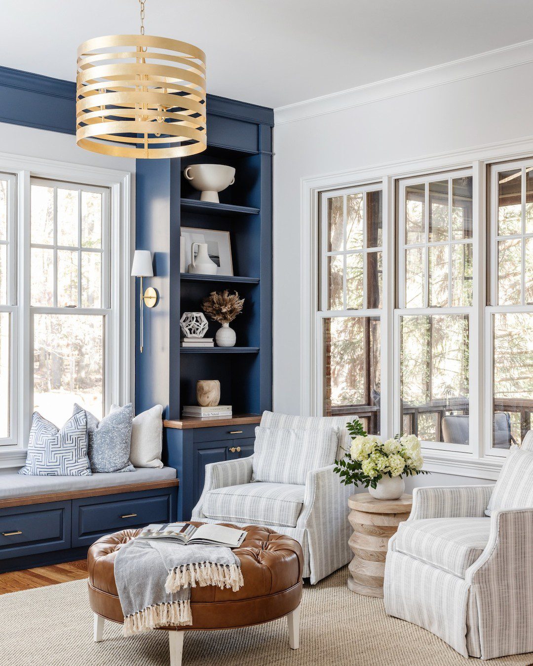 Cozy nook with built-in seating and navy blue shelving, accentuated by a striking gold pendant light.