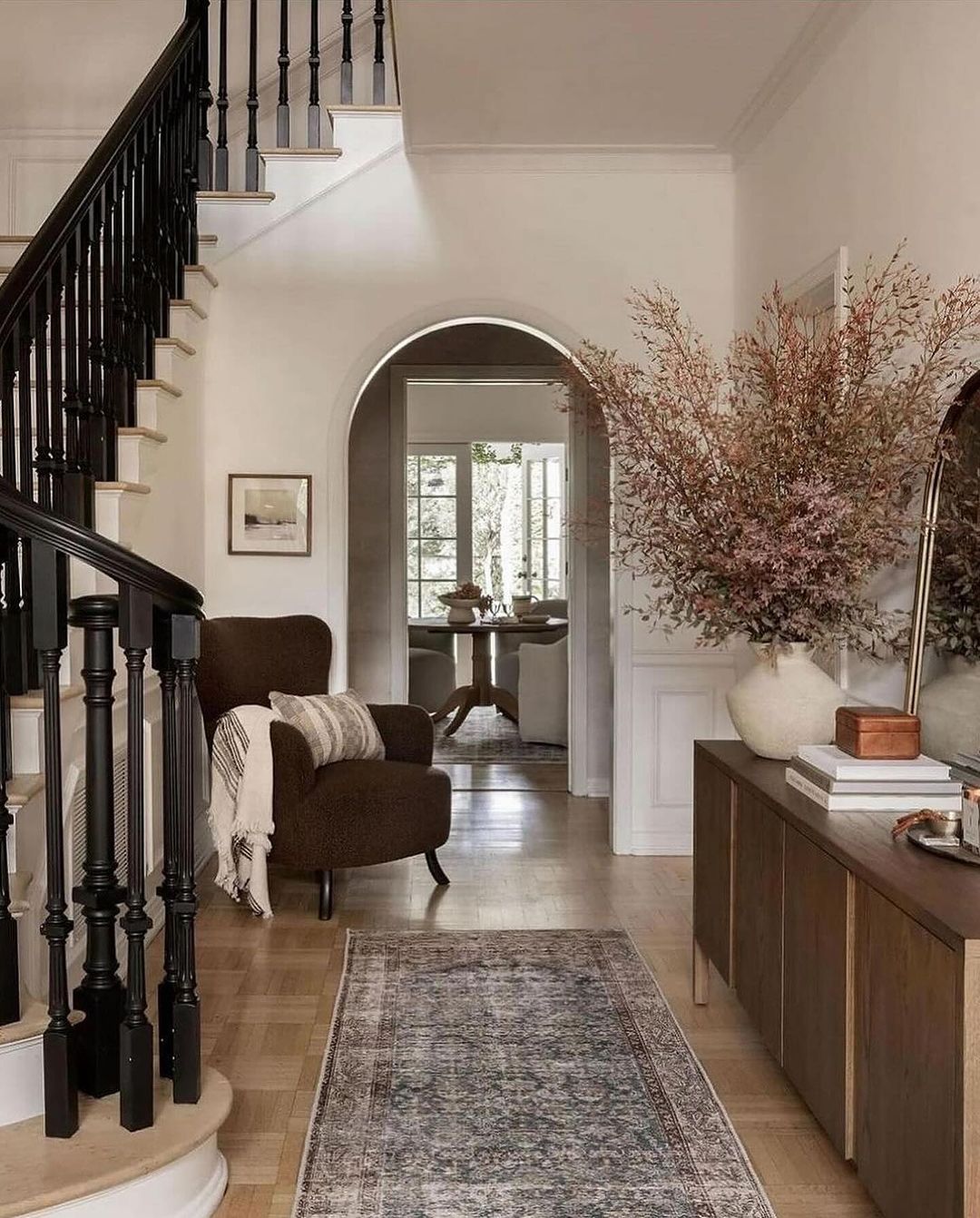 A cozy and inviting entryway featuring a bold black staircase and hints of natural textures