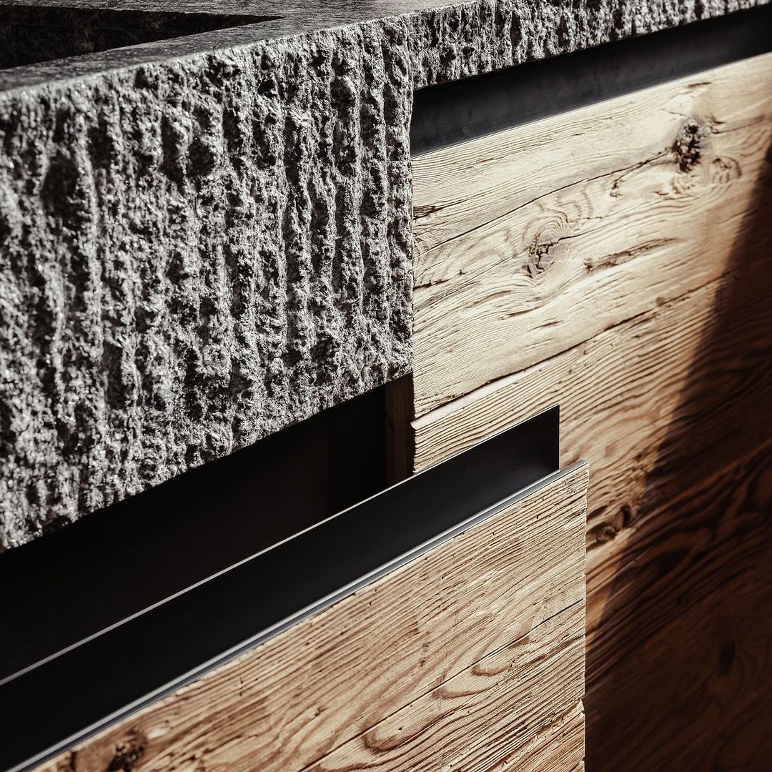 The interplay of textures with rough stone, sleek metal, and warm wood