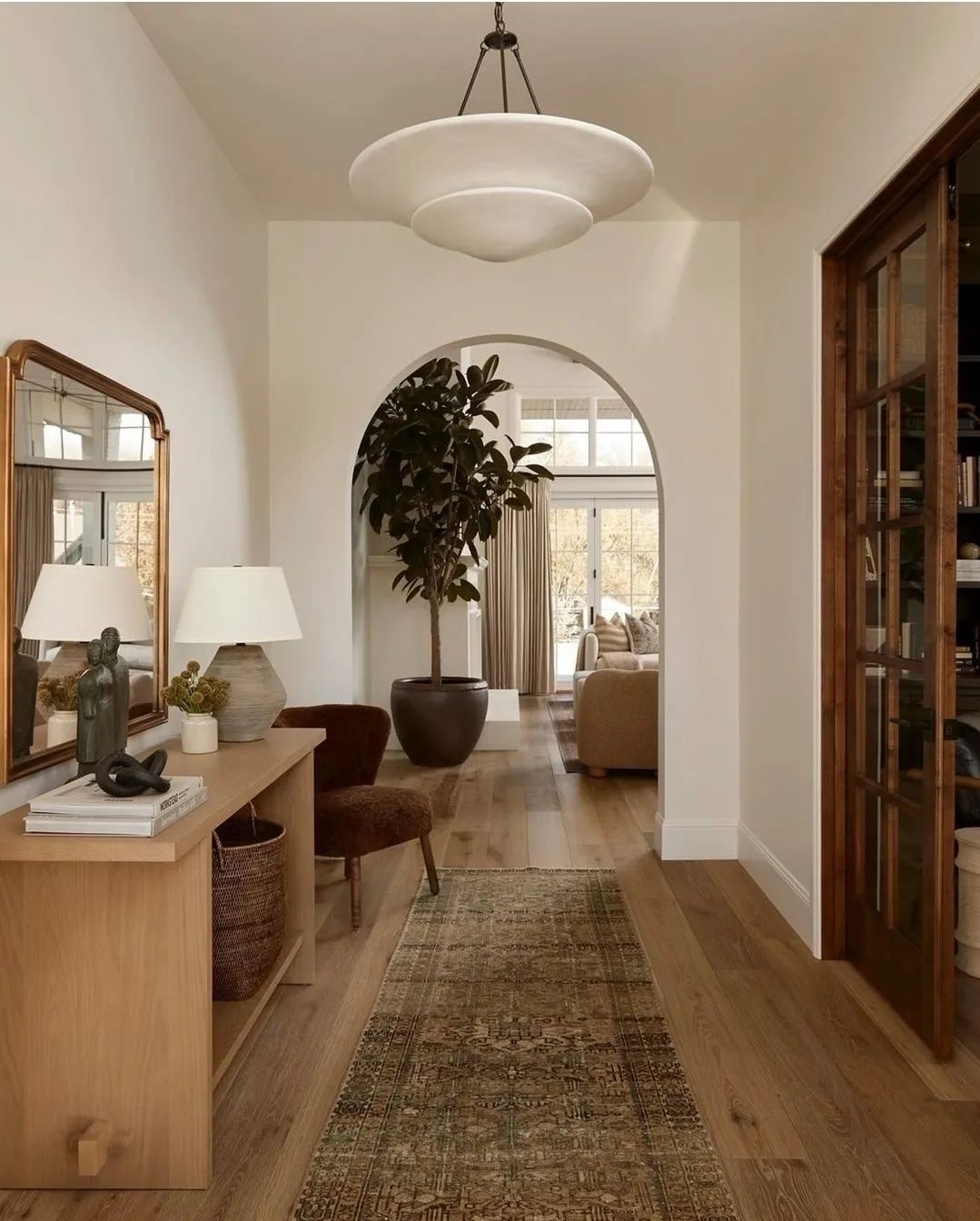 A warm and inviting interior featuring arched doorways, a large pendant light, and wooden design elements