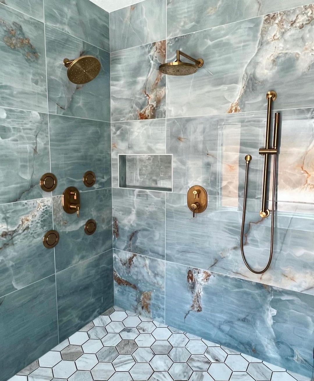 Luxuriously appointed blue marble-tiled shower with brass fixtures