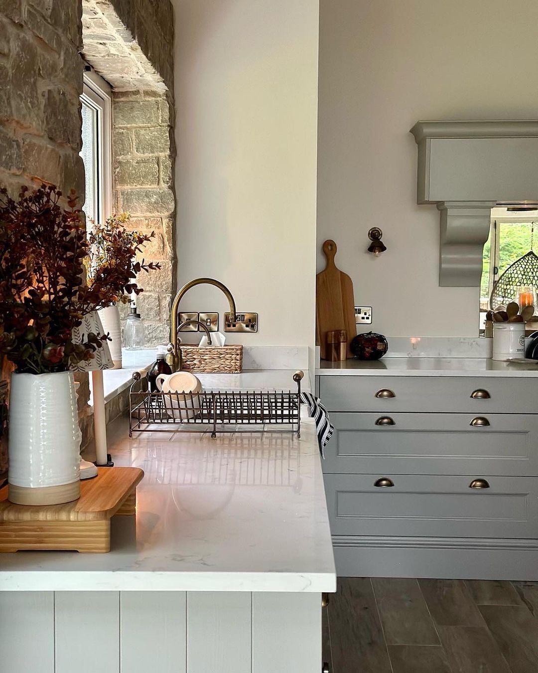 A harmonious blend of rustic charm and modern simplicity is showcased in this kitchen, featuring stone walls and sleek grey cabinetry.