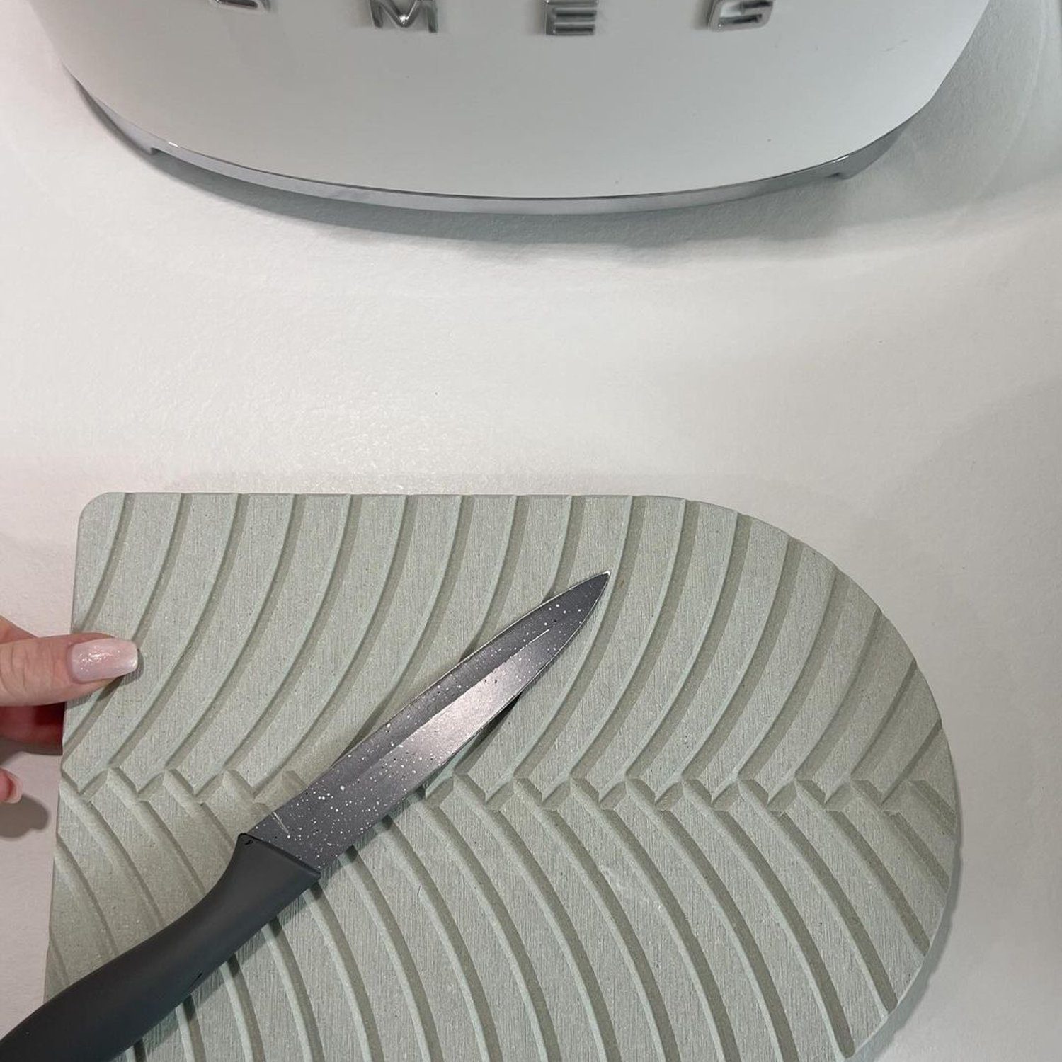 A knife laying on a uniquely textured cutting board