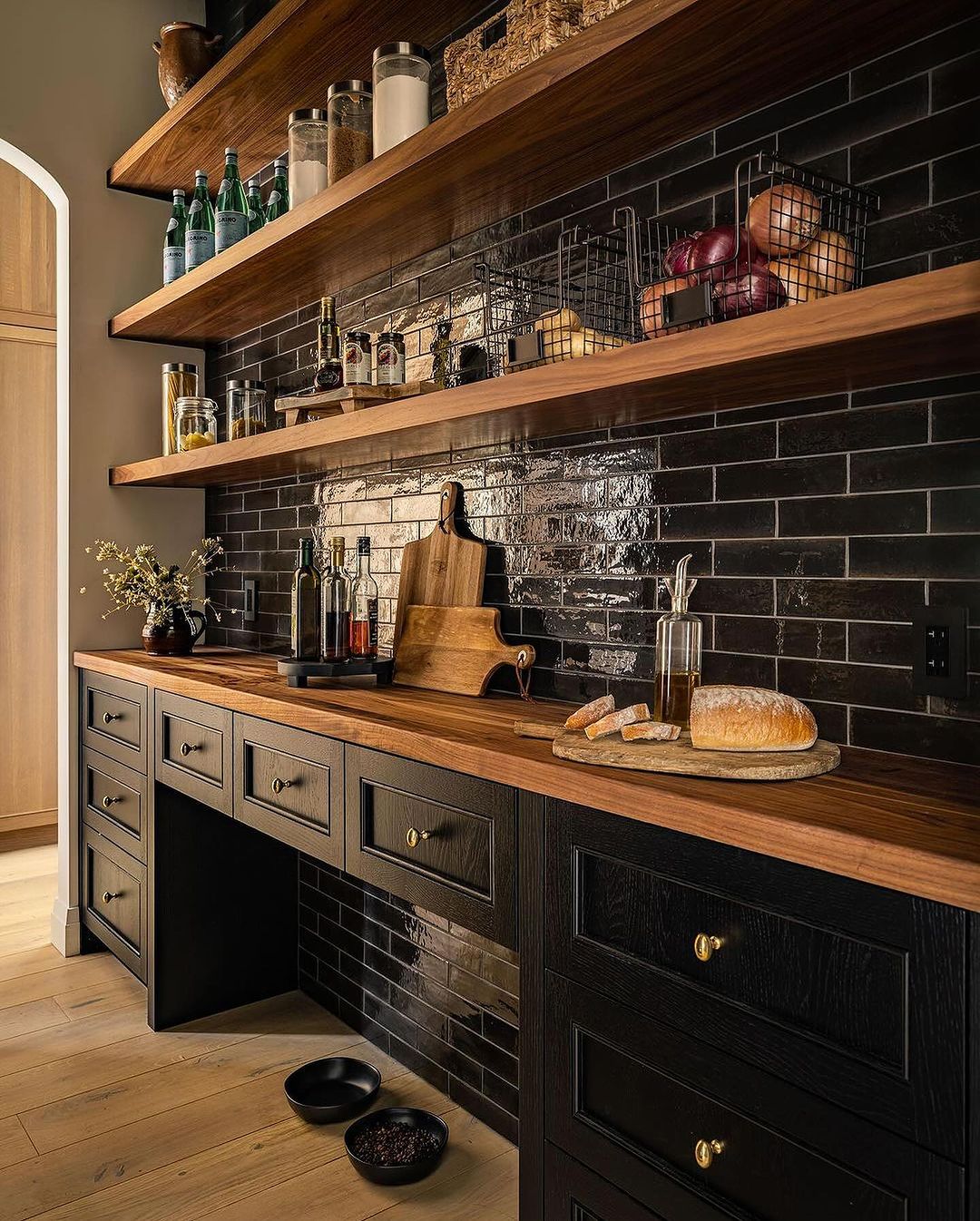 A modern kitchen space featuring dark subway tile backsplash and rich wooden countertops