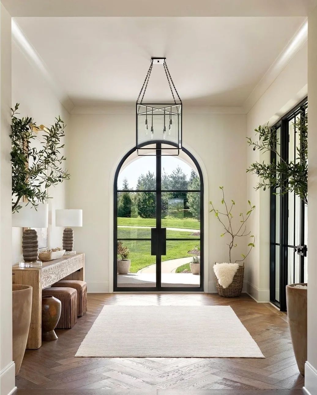 A serene and harmonious entryway designed with a welcoming symmetrical layout, featuring a large arched doorway, high ceilings, and a balanced arrangement of neutral-toned furniture and natural elements.