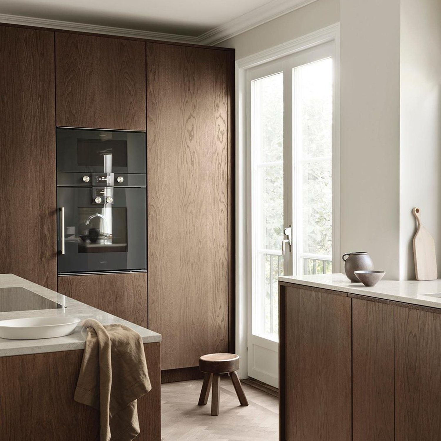 A minimalist kitchen featuring integrated dark wood cabinetry, a built-in coffee machine, and a discreet undermount sink