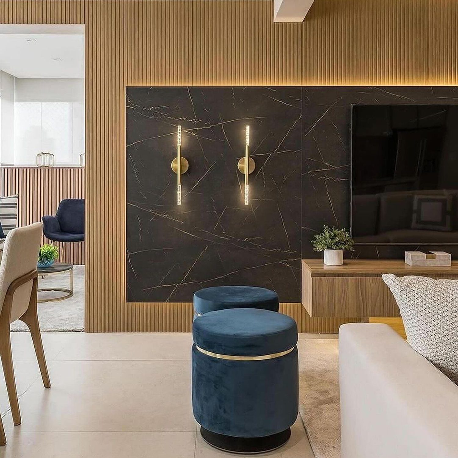 A sleek and modern living room featuring a dark marble entertainment wall with brass sconces and a ribbed wood accent