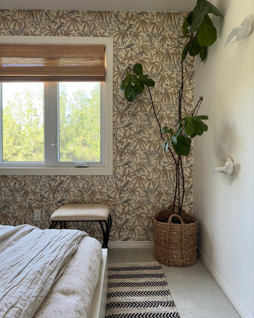 Cozy corner of a modern bedroom with botanical wallpaper and natural light