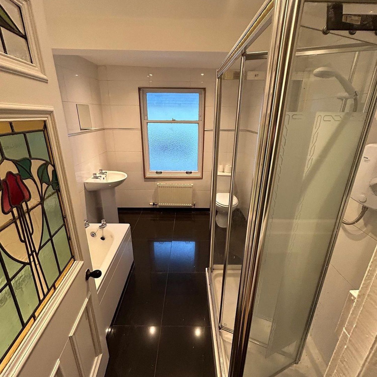 A modern and sleek bathroom featuring high gloss black floor tiles