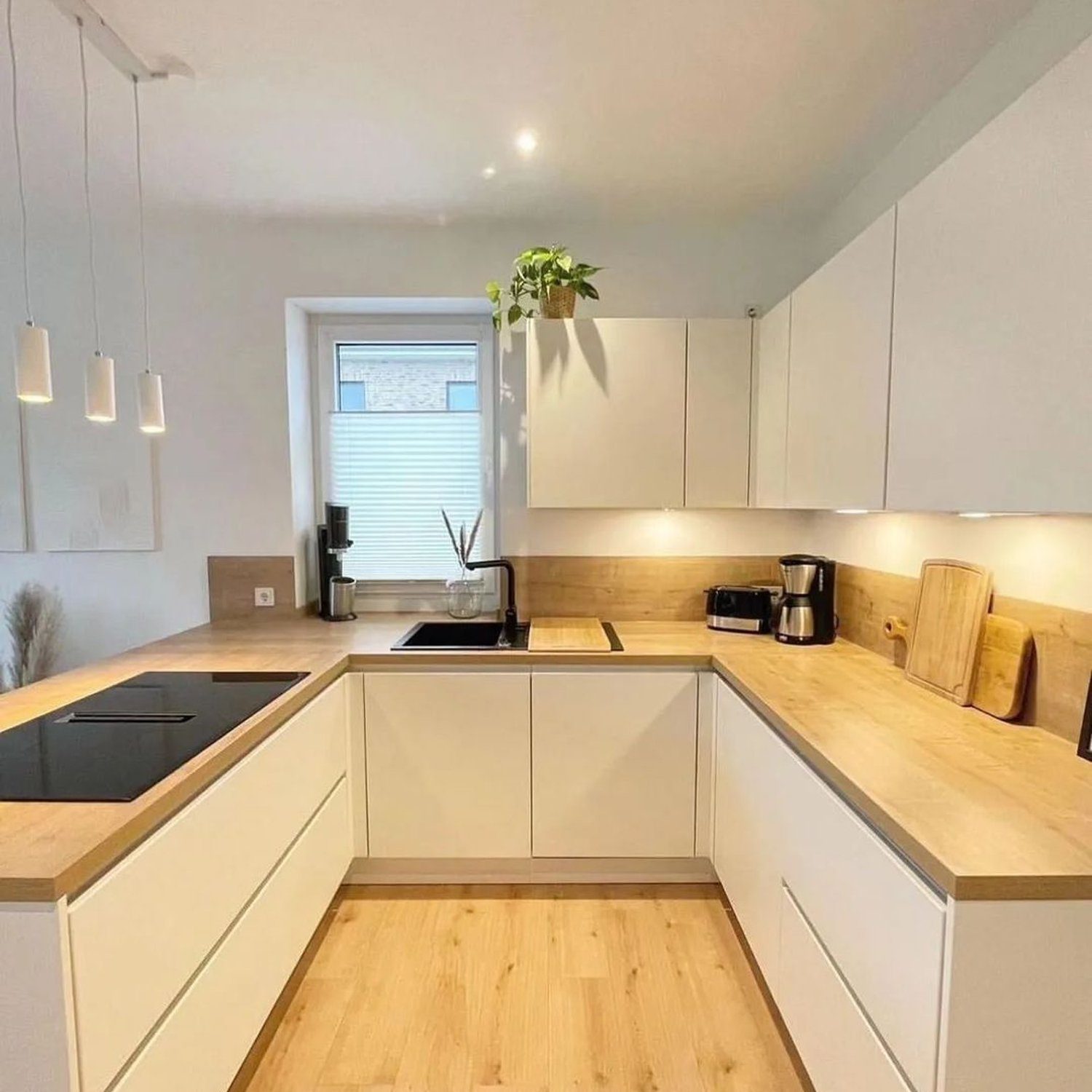 A modern, clean kitchen with sleek white cabinets, wooden countertops, and stainless steel appliances.