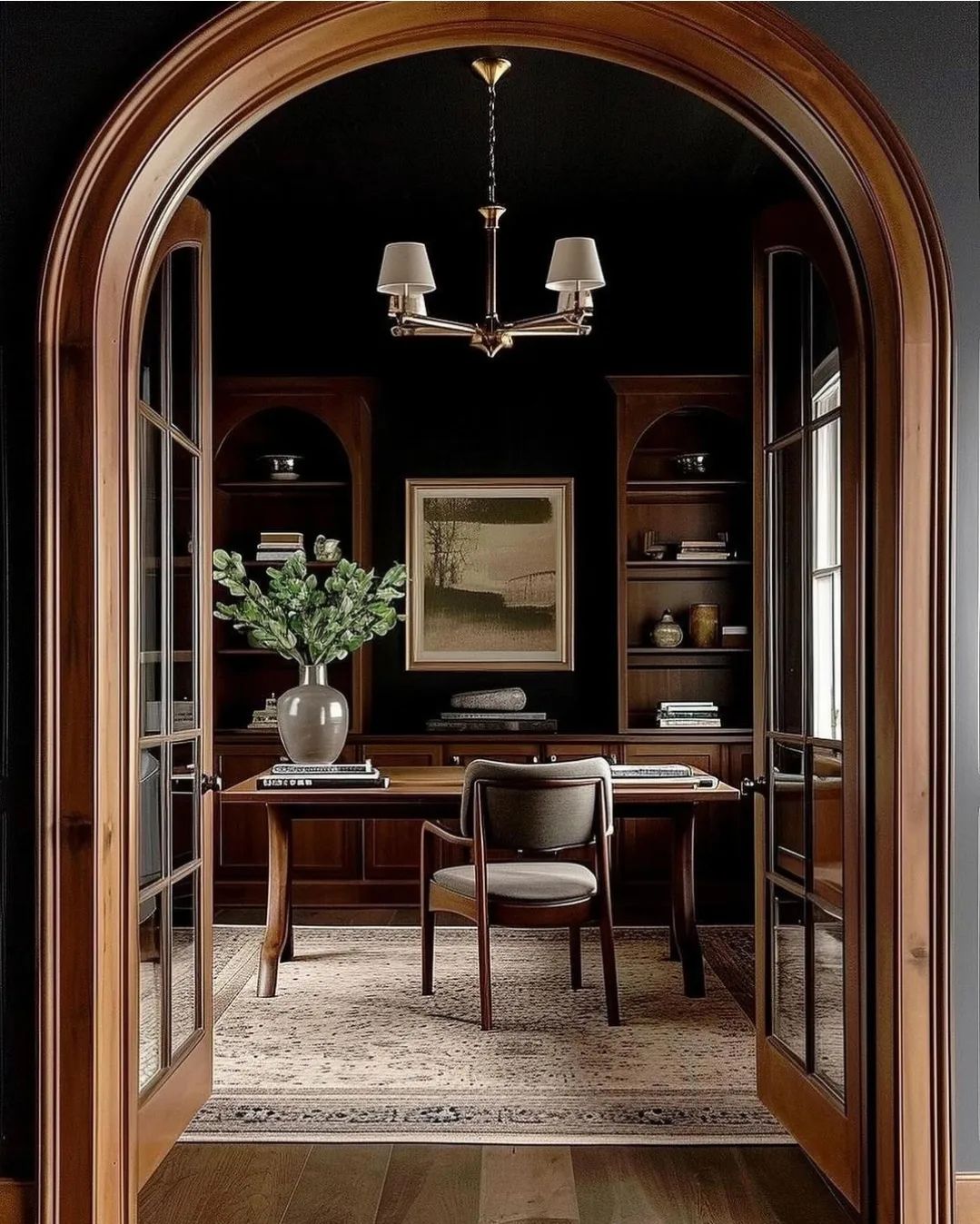 A thoughtfully designed study with arched wooden entryway and dark walls