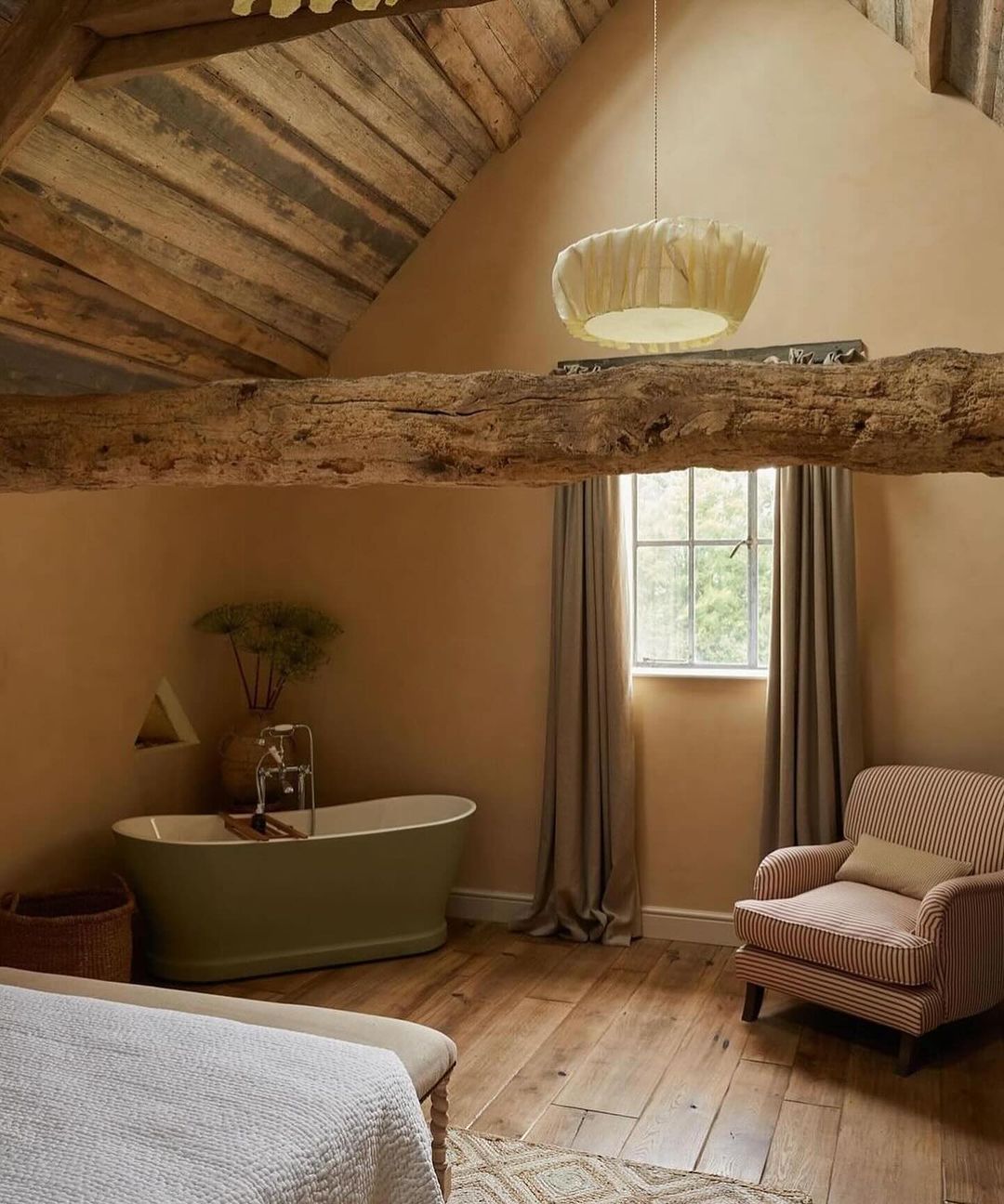 A serene attic bathroom featuring exposed wooden beams and a standalone bathtub