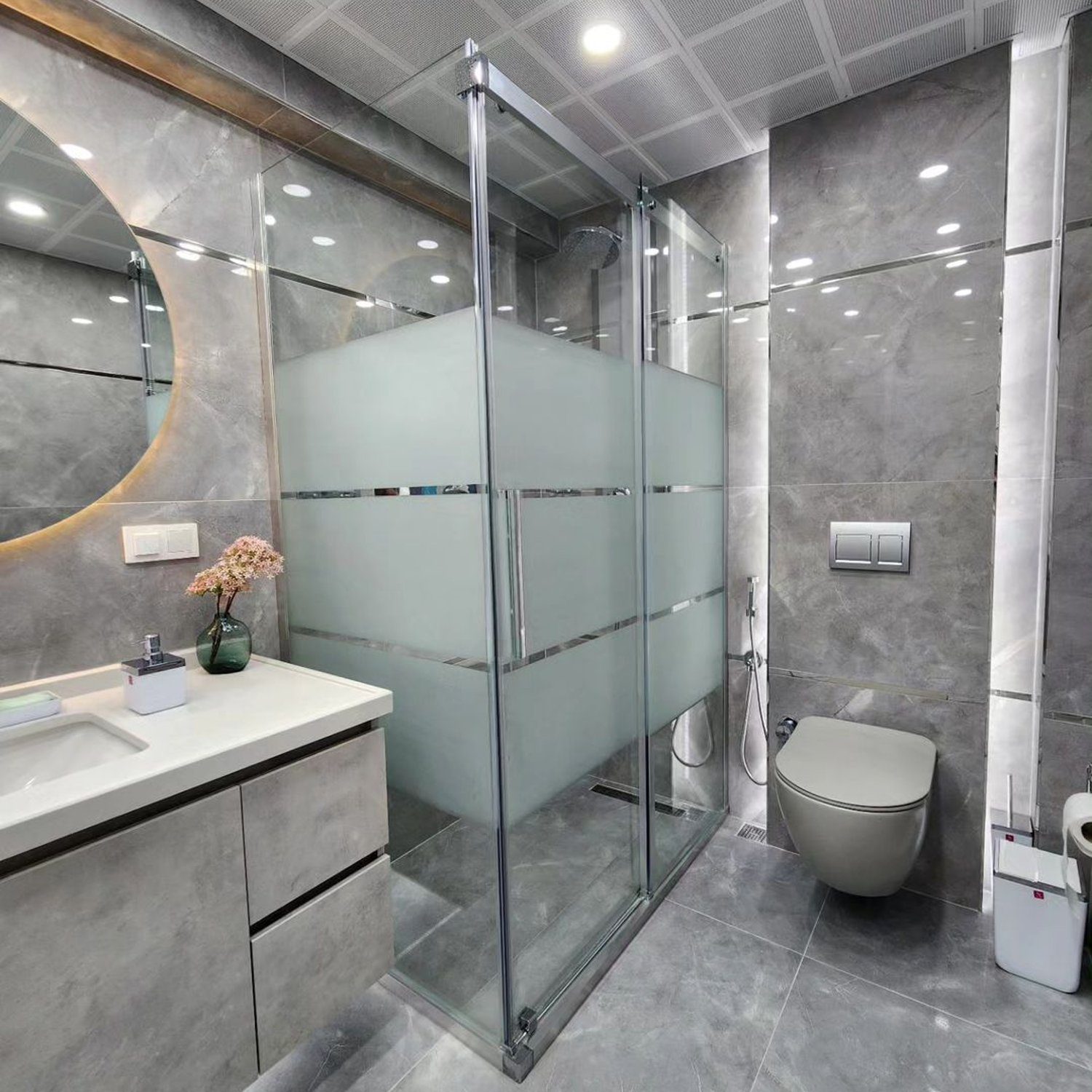 Modern and stylish bathroom with grey tiles and glass shower cabin