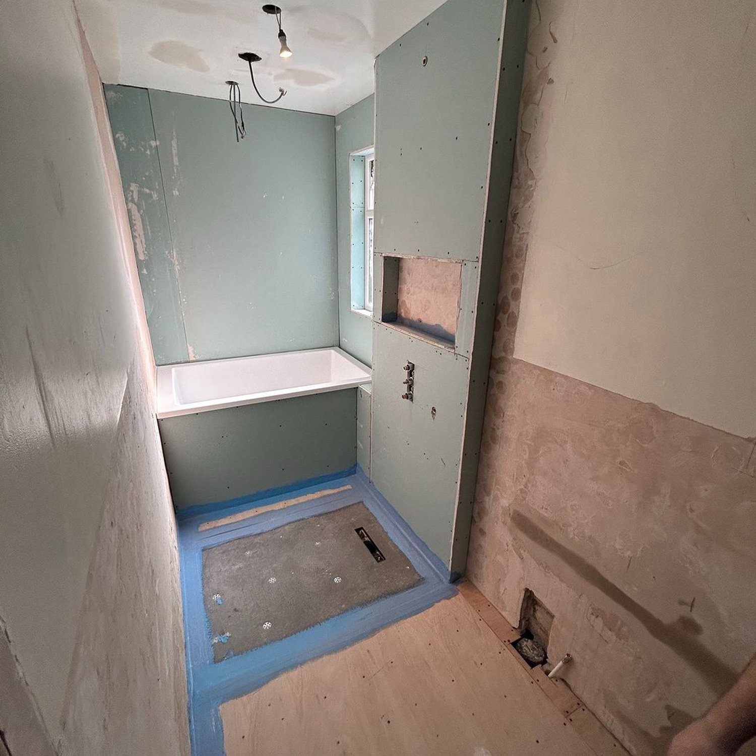 A room mid-renovation showing exposed walls and a bathtub