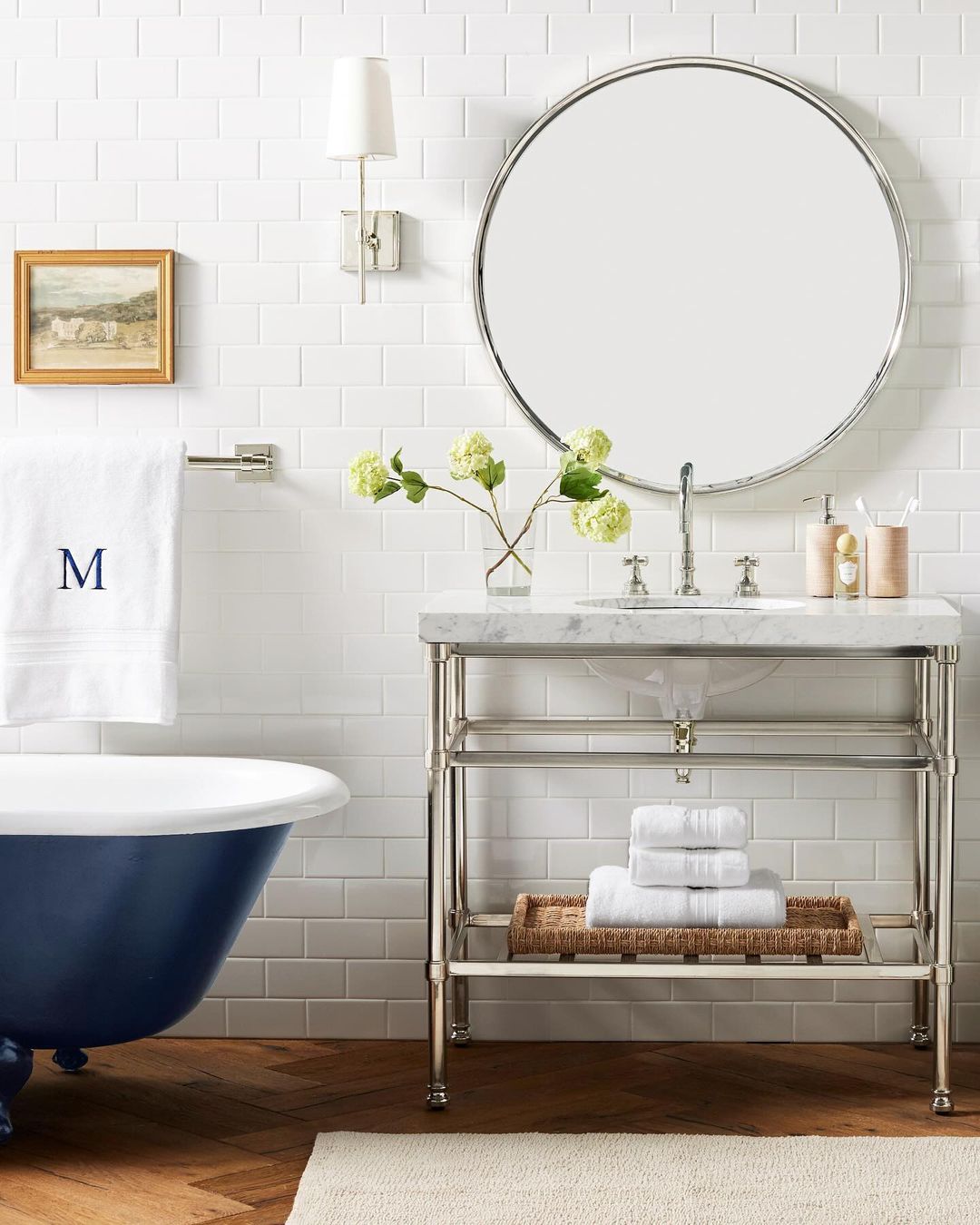 A chic blue and white bathroom featuring subway tiles and a clawfoot tub