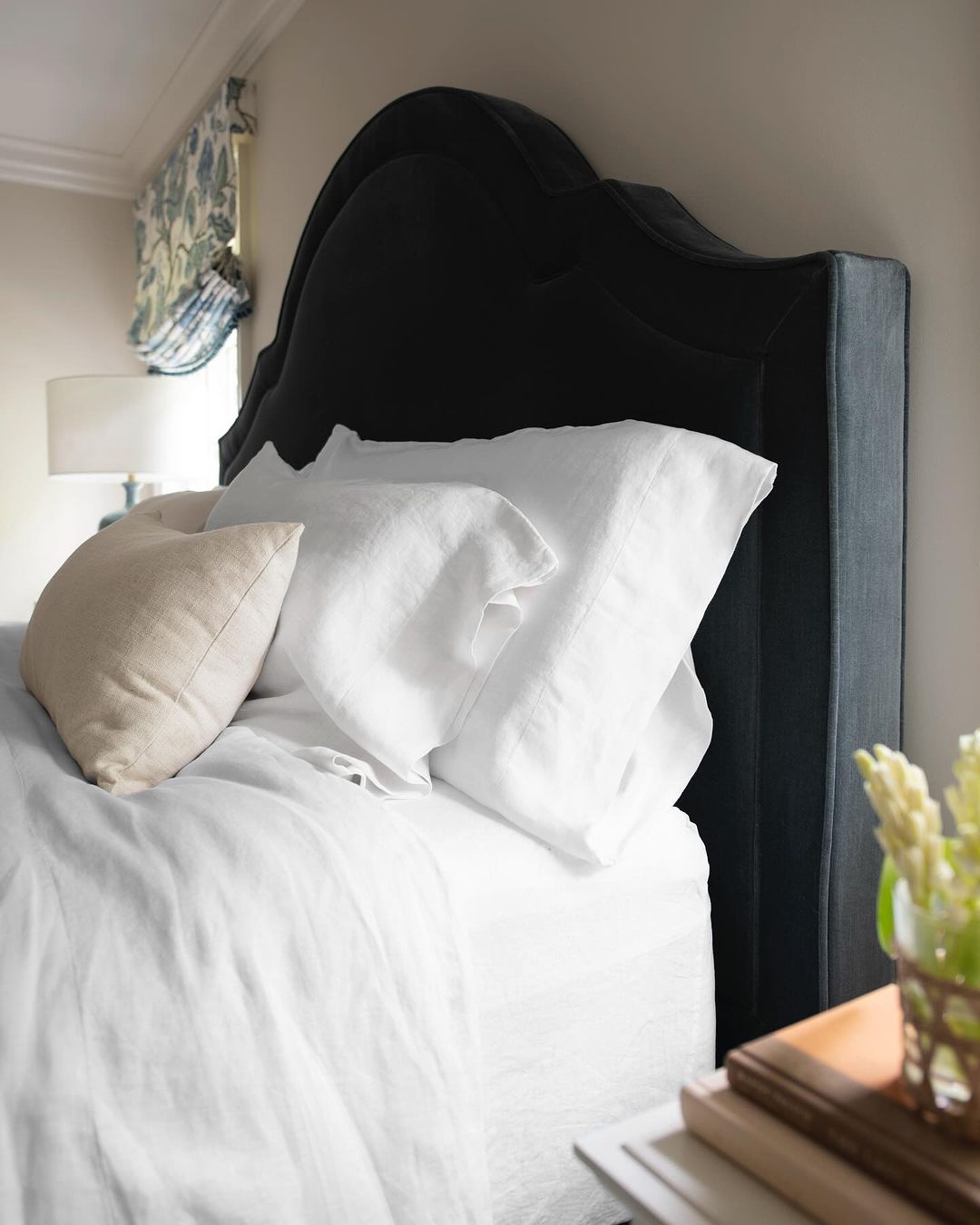 A cozy and well-appointed bedroom focusing on a plush bed with a stylish black headboard