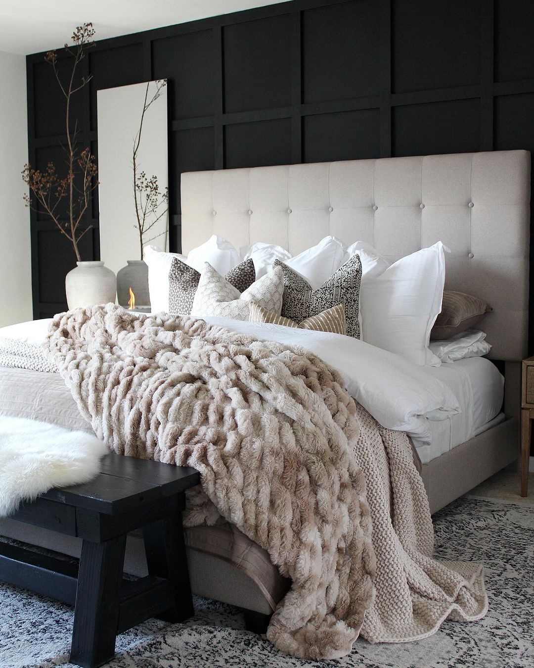 A chic and cozy bedroom featuring a black accent wall