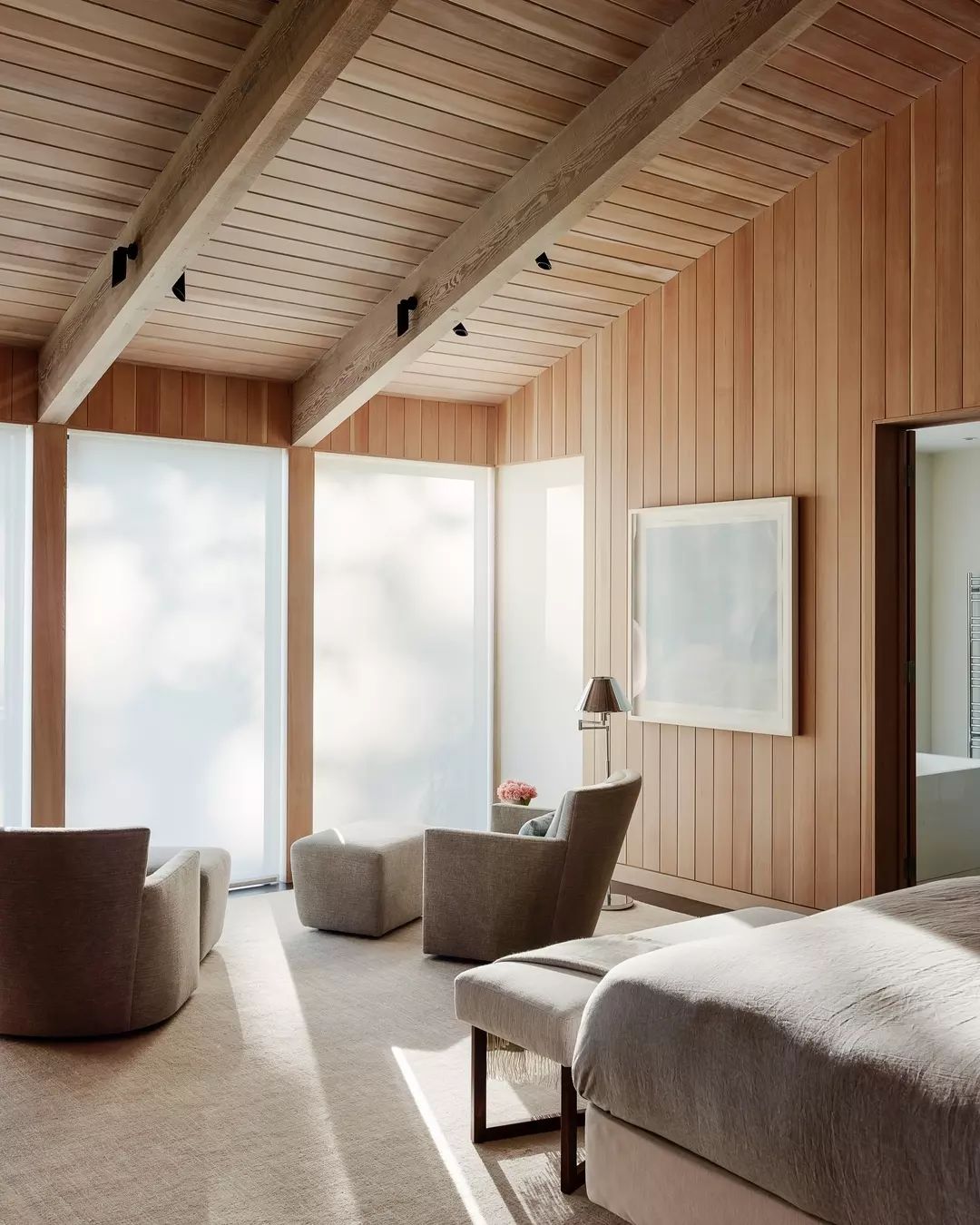 A warm and inviting bedroom featuring exposed wooden beams and vertical paneling