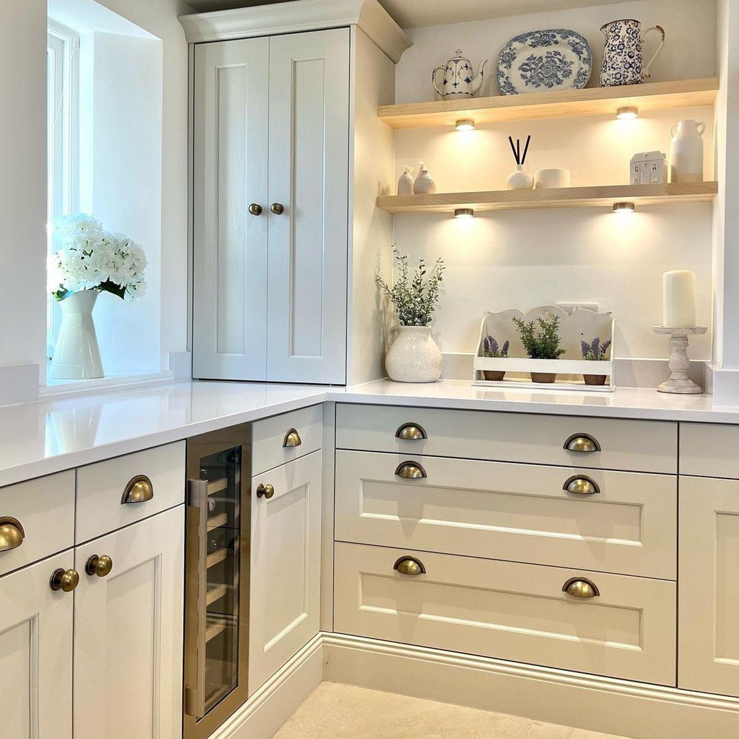 Elegant beige-toned kitchen corner with open shelving displaying decorative items