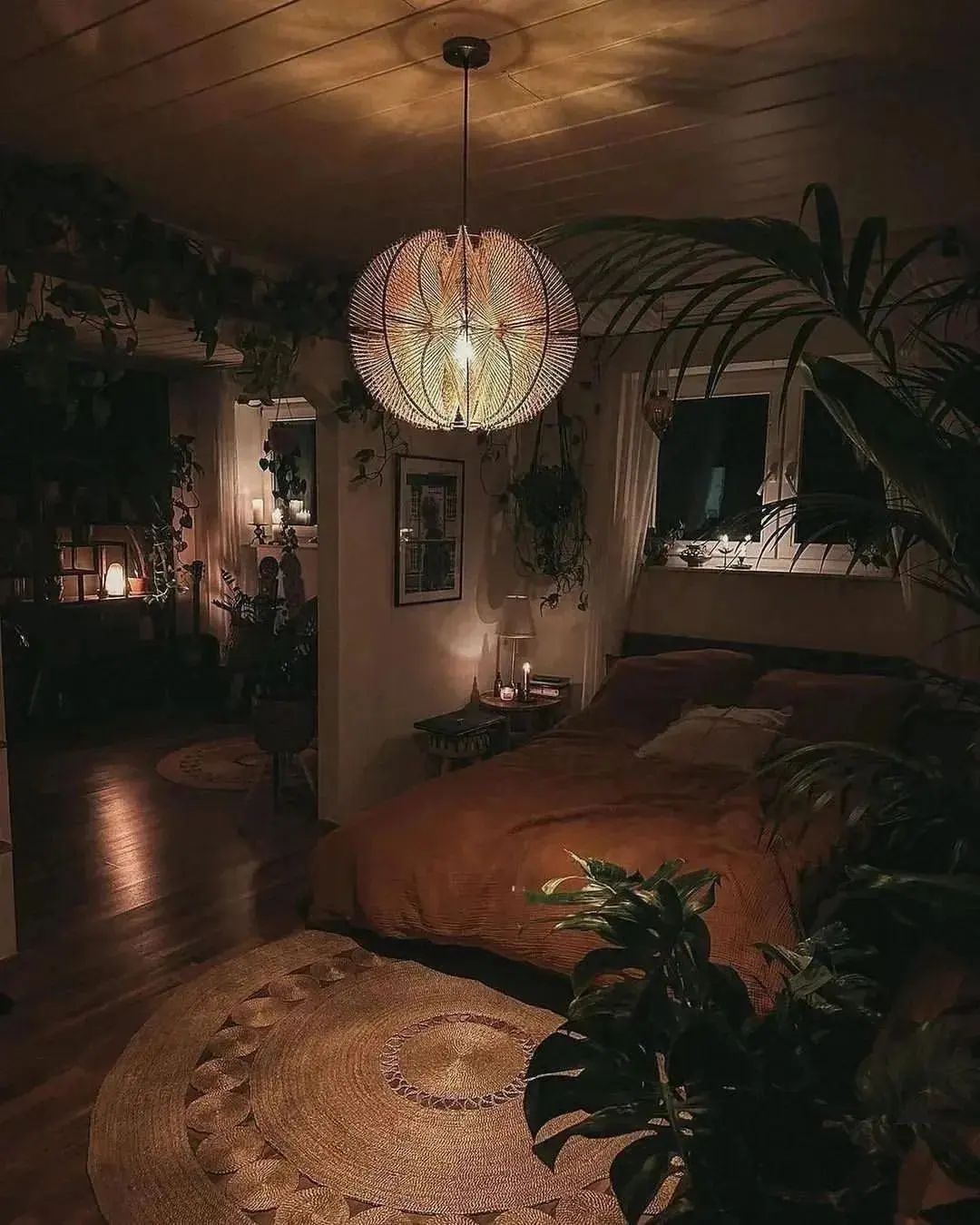 A cozy and warm bedroom setting with ample plants and soft lighting