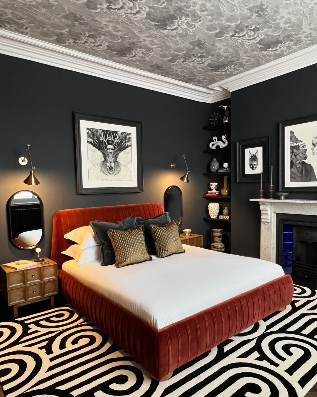 A bold and dramatic bedroom featuring an orange velvet bed, dark walls, and a striking zebra-patterned rug.