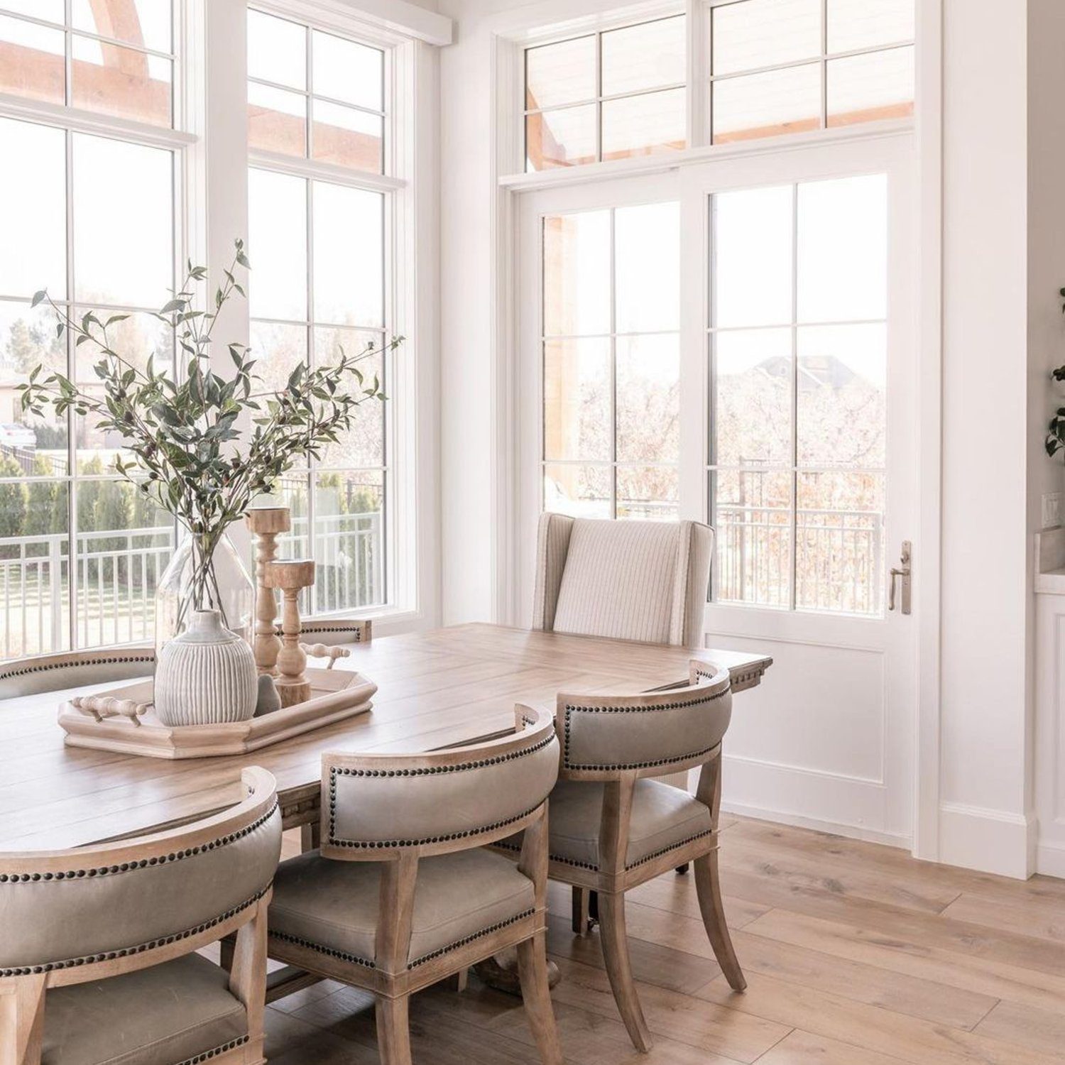 A serene and spacious dining room with large windows offering natural light and a view of the outdoors