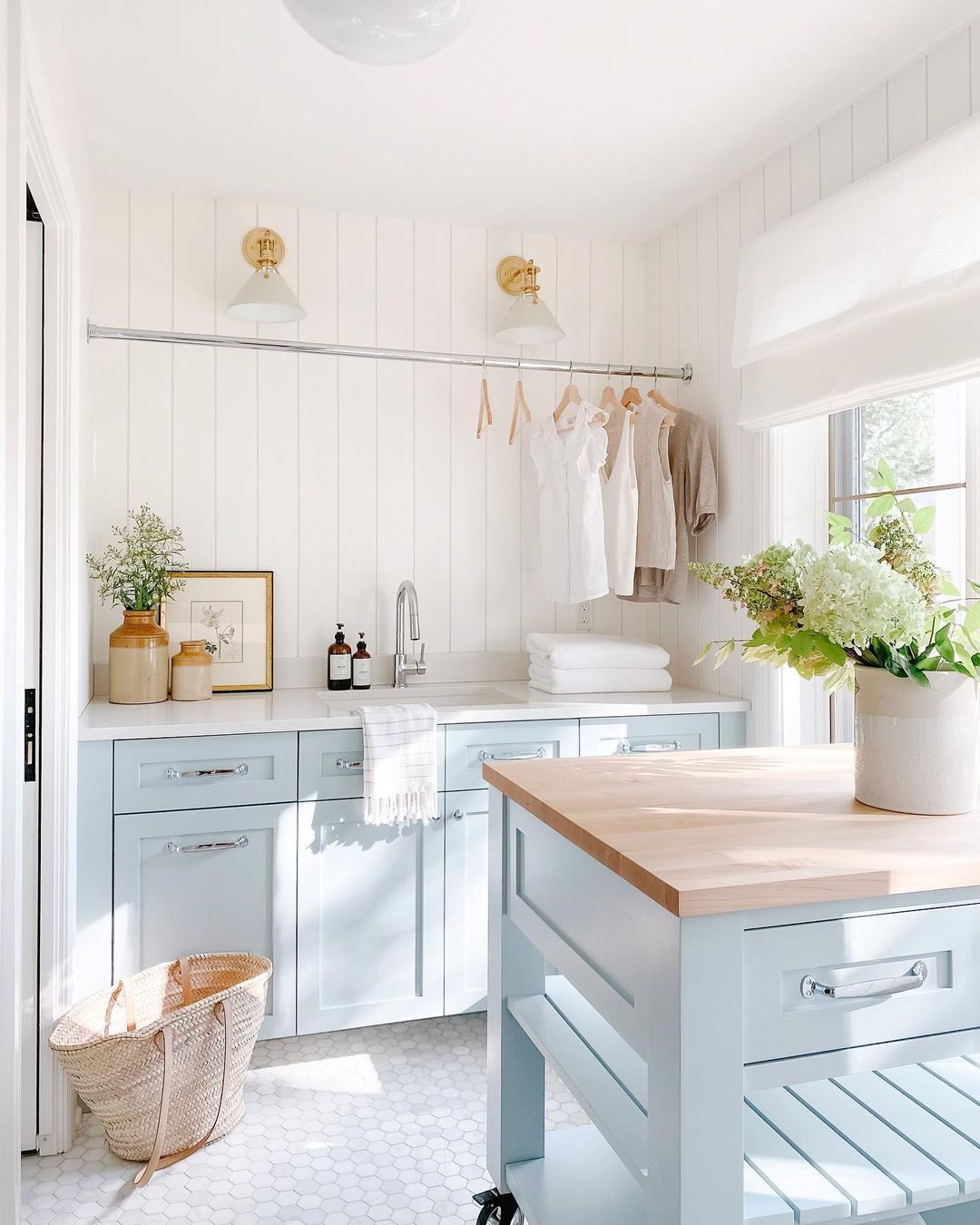 Bright and airy laundry room with blue cabinetry and wooden countertops