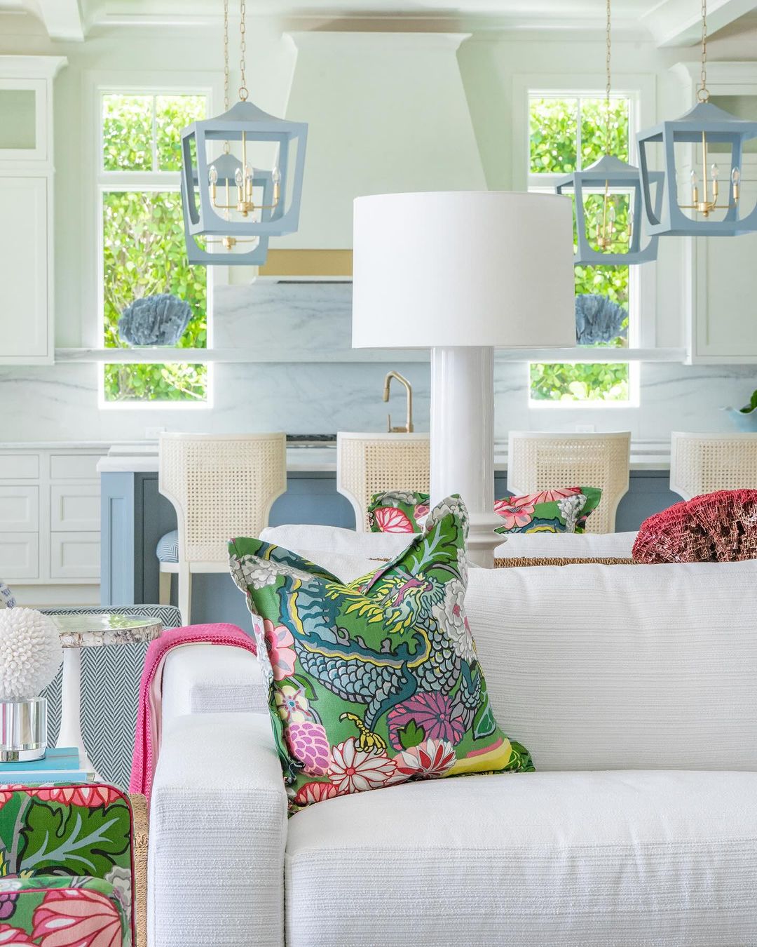 A vibrant and inviting living room design featuring a cozy white sofa adorned with brightly patterned pillows, set against a backdrop of crisp white walls, striking blue accents, and natural light filtering through large windows.