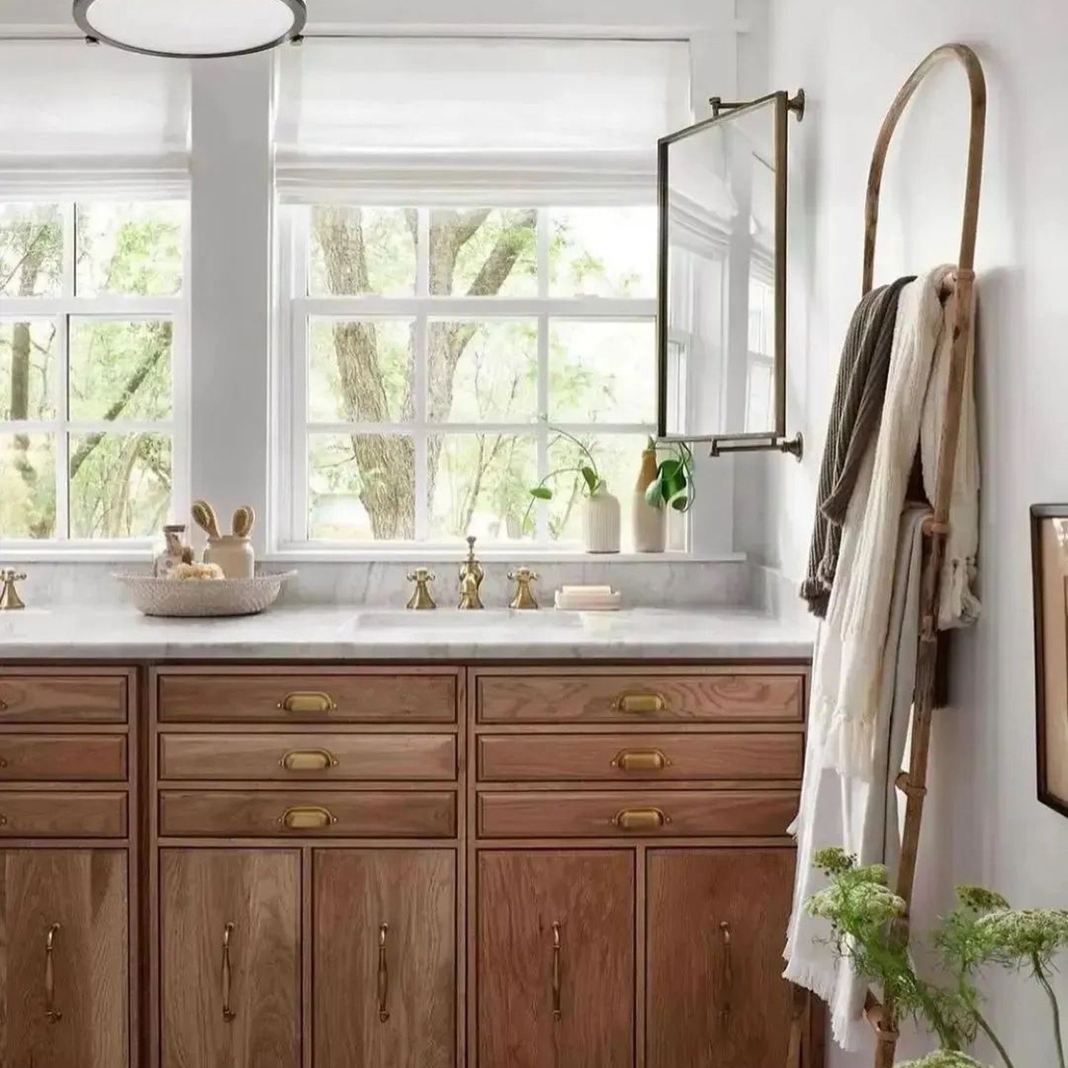 Elegant wooden bathroom cabinetry with brass fixtures in a bright setting