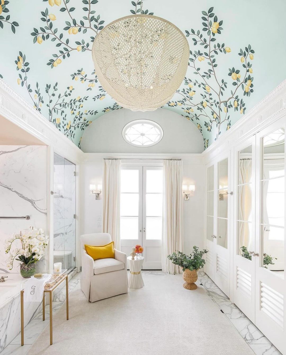 A tastefully appointed bathroom featuring pastel-hued floral ceiling wallpaper and marble accents