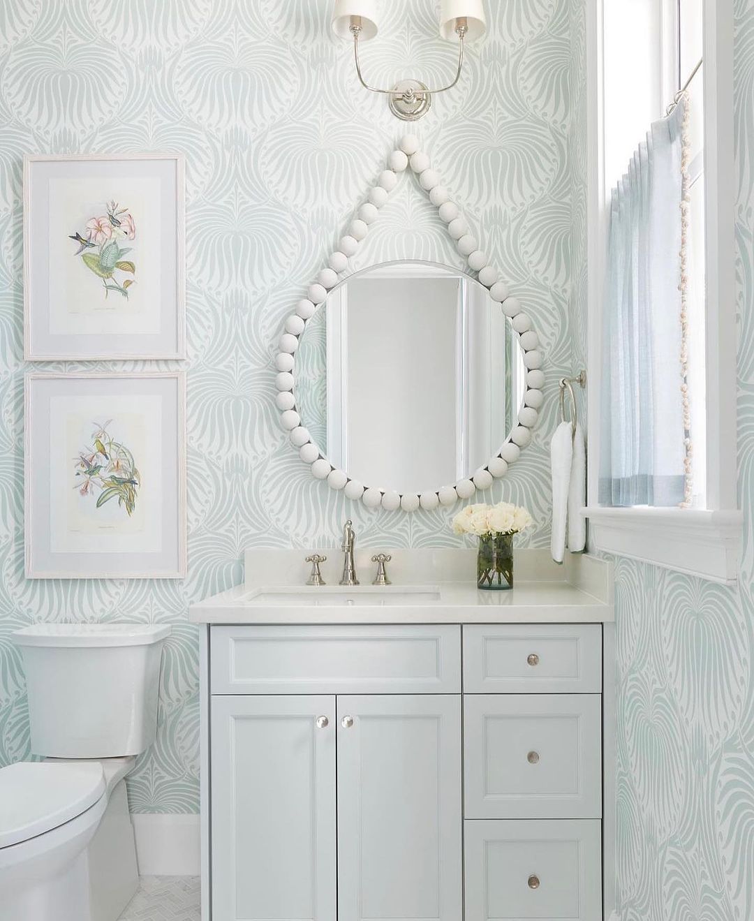 Chic bathroom with patterned wallpaper and a unique beaded mirror