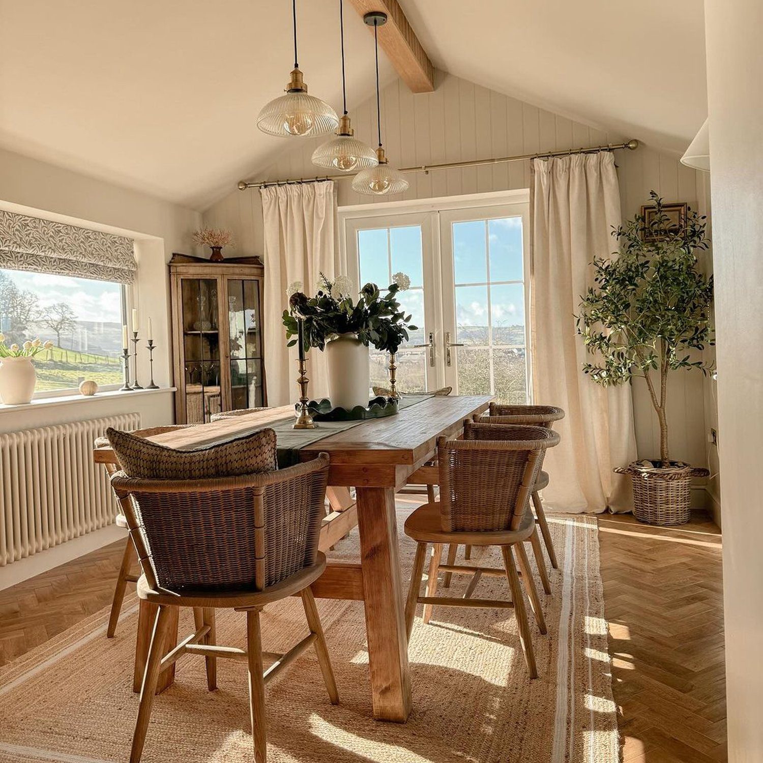 A cozy dining room with abundant natural light and rustic wooden furniture.