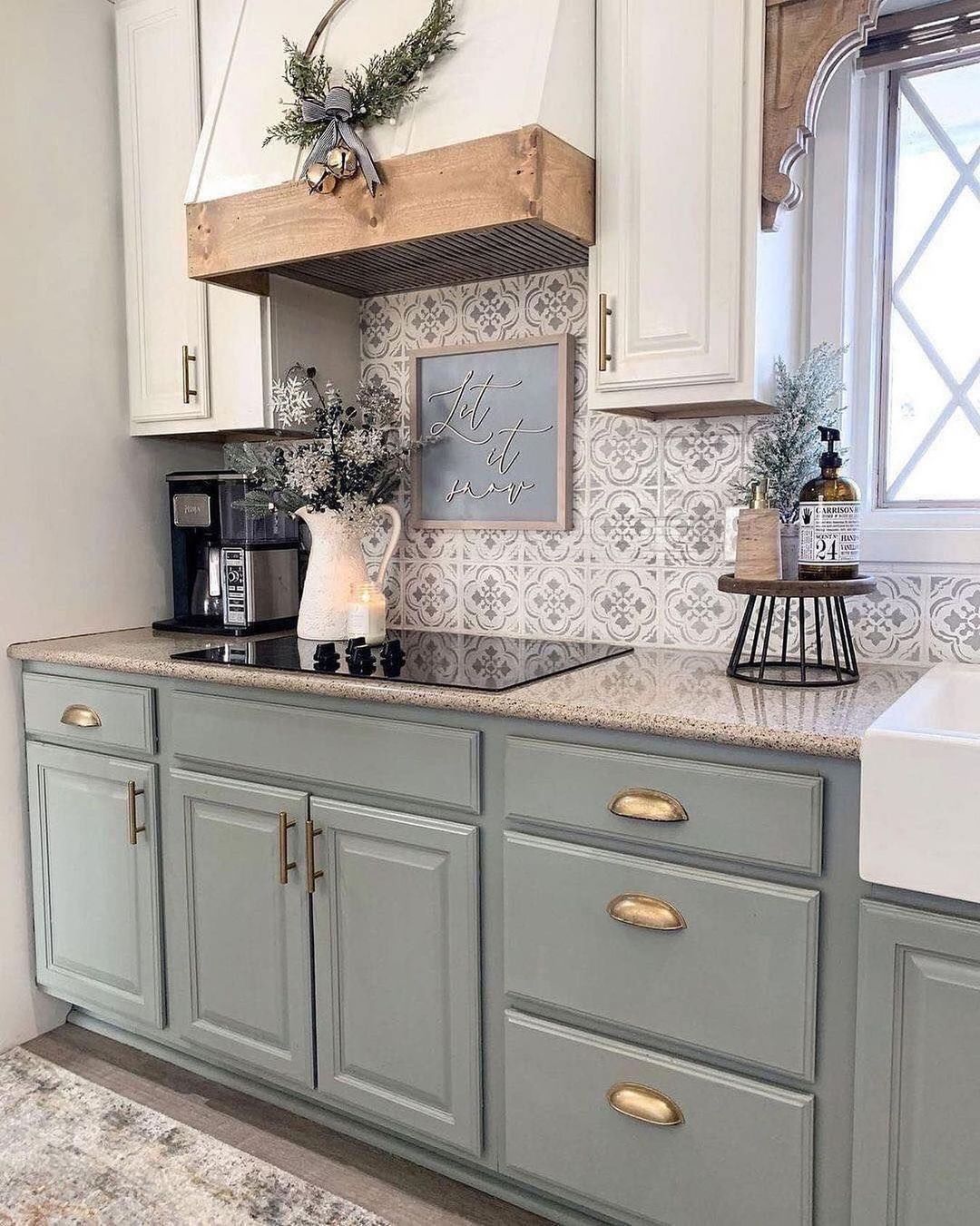 A tastefully designed kitchen space highlighting soft sage cabinetry with brass hardware