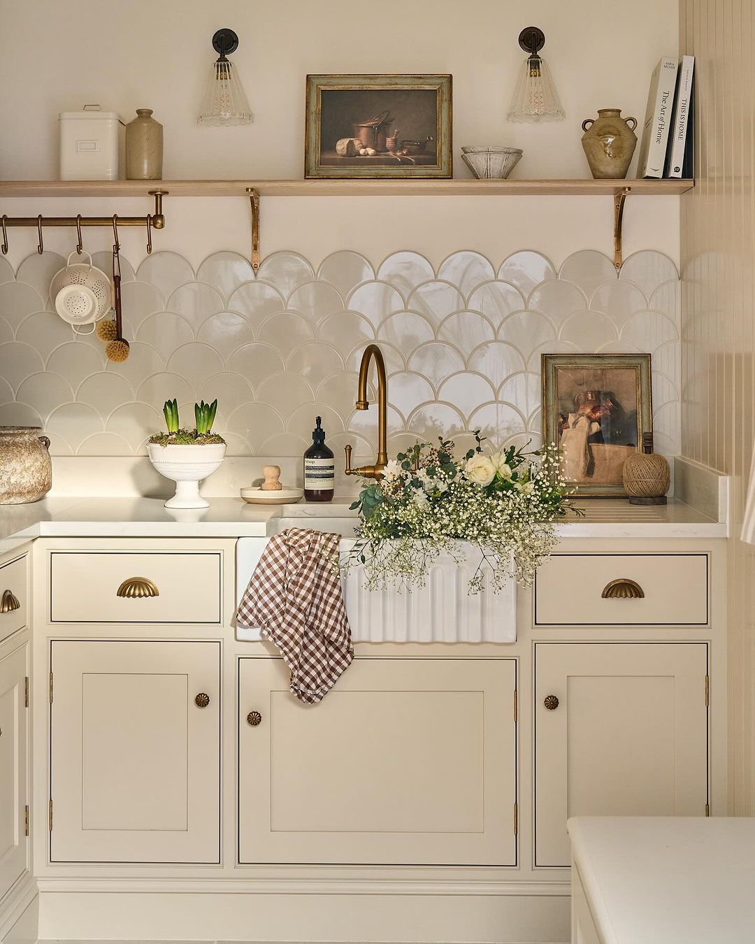 A harmonious blend of classic and contemporary elements featuring scalloped tile backsplash, brass accents, and ceramic decor