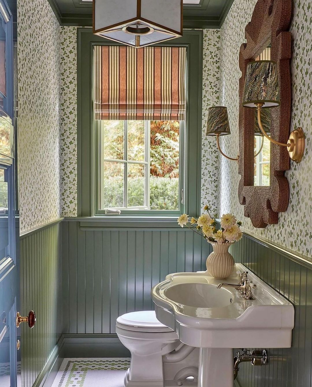 A charming vintage-style bathroom with patterned wallpaper and green beadboard