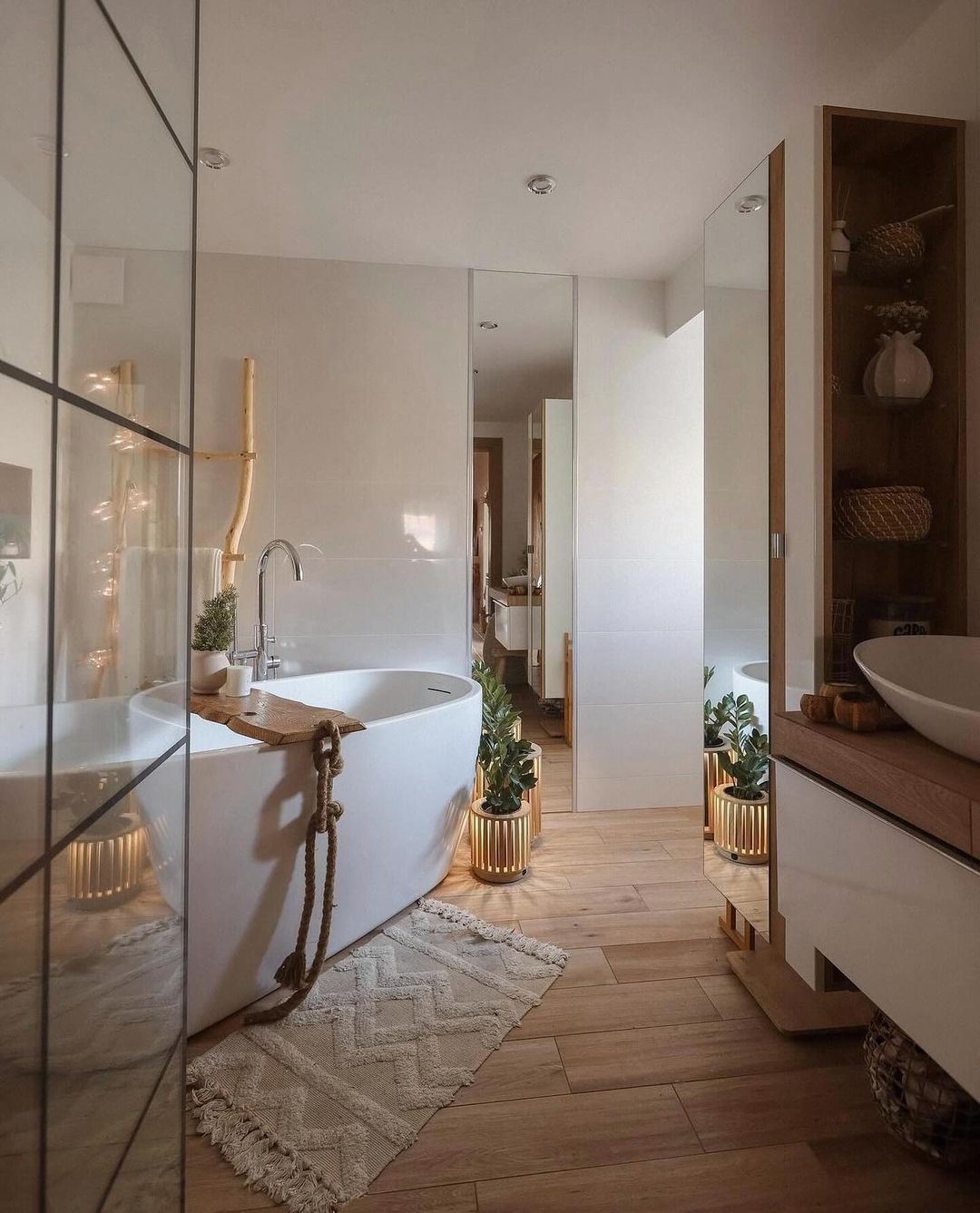 A modern bathroom featuring a free-standing bathtub with a rustic rope handle, complemented by wooden accents and fresh green plants.