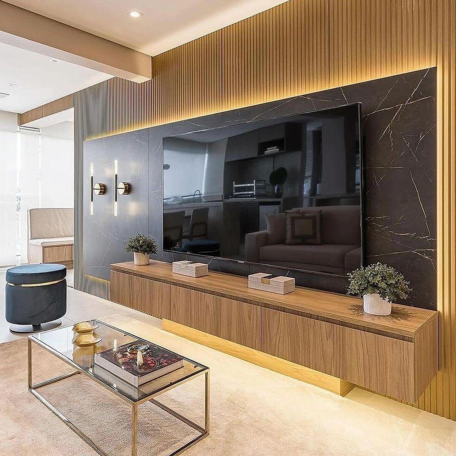 An elegantly designed living room featuring a wood and brass media console with integrated lighting beneath a large black marble wall-mounted TV.