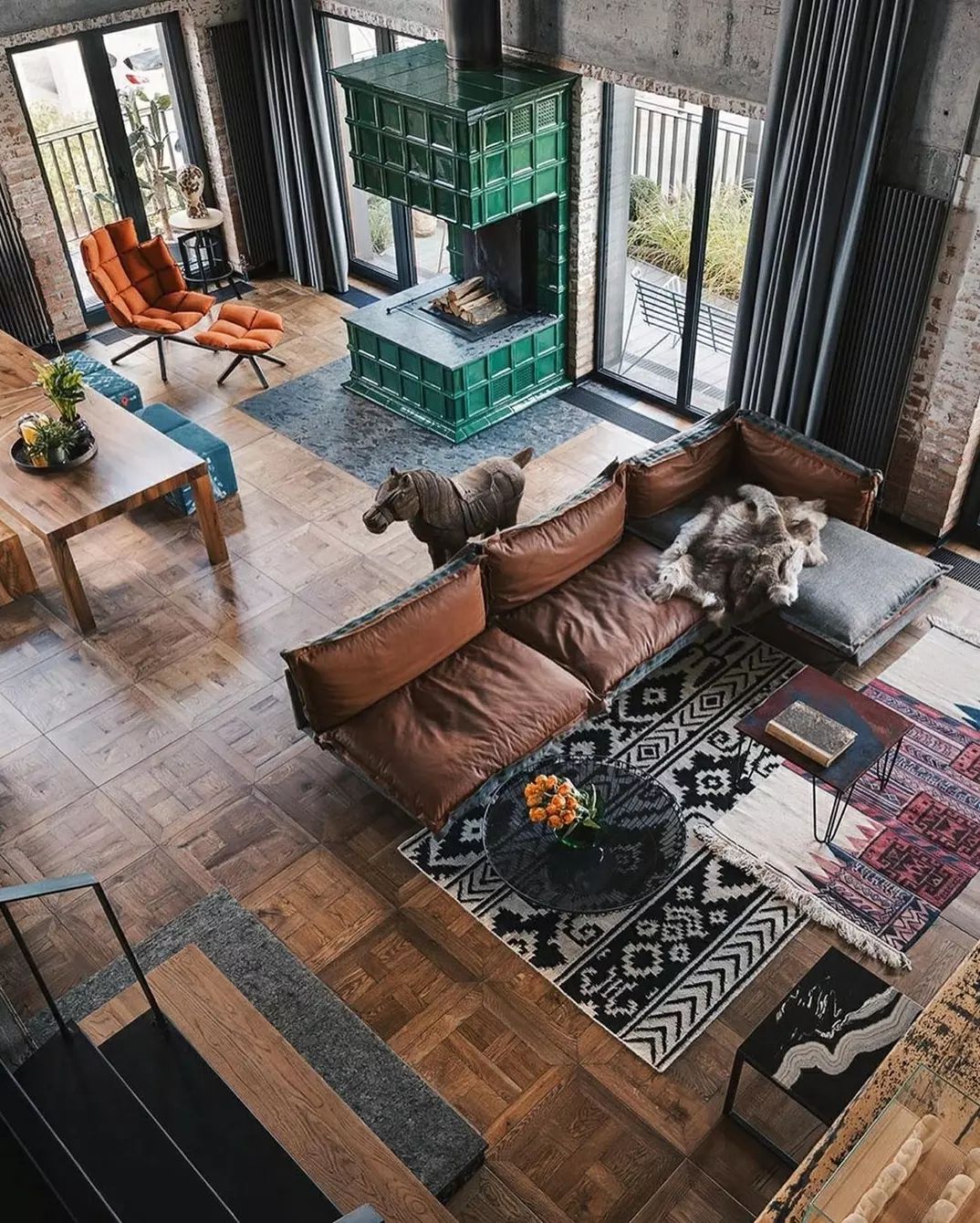 A chic industrial-style living room featuring a modular brown sofa and a striking green fireplace