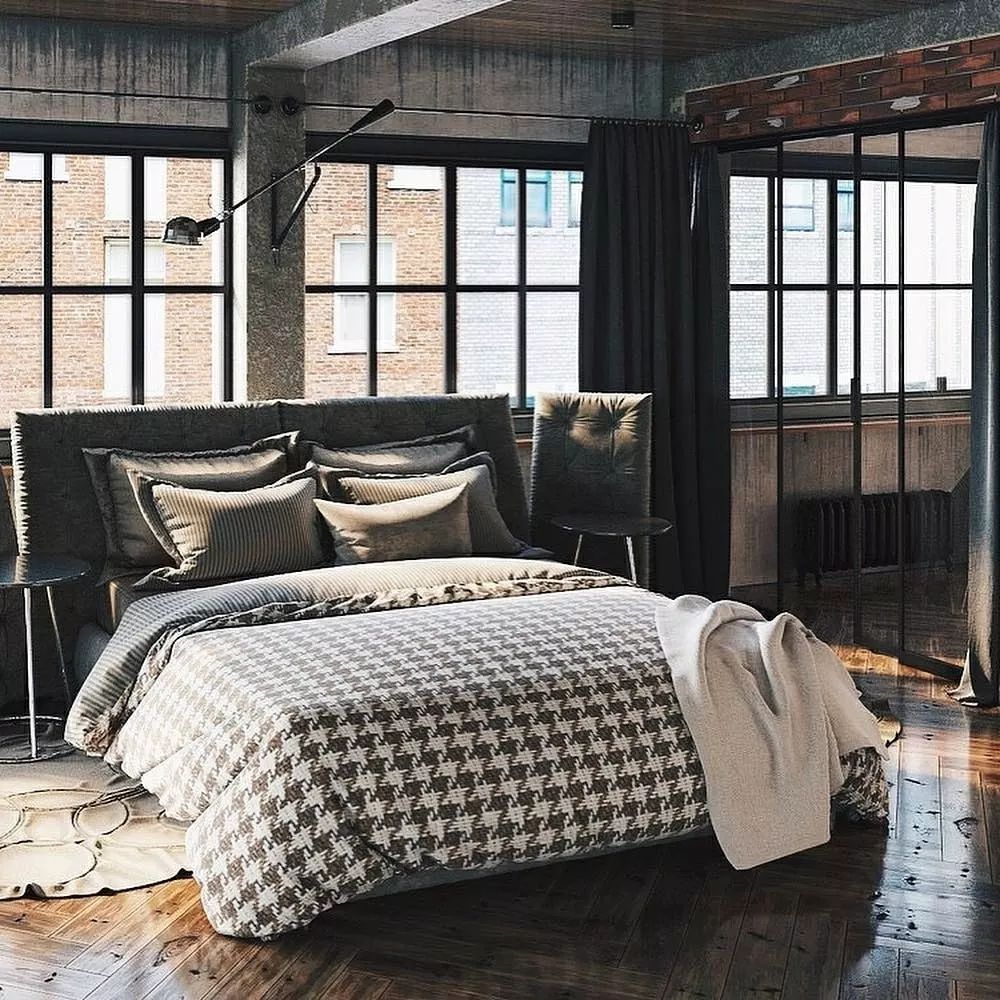 A chic and cozy industrial bedroom featuring exposed concrete beams and brickwork, with a plush bed adorned with patterned bedding.