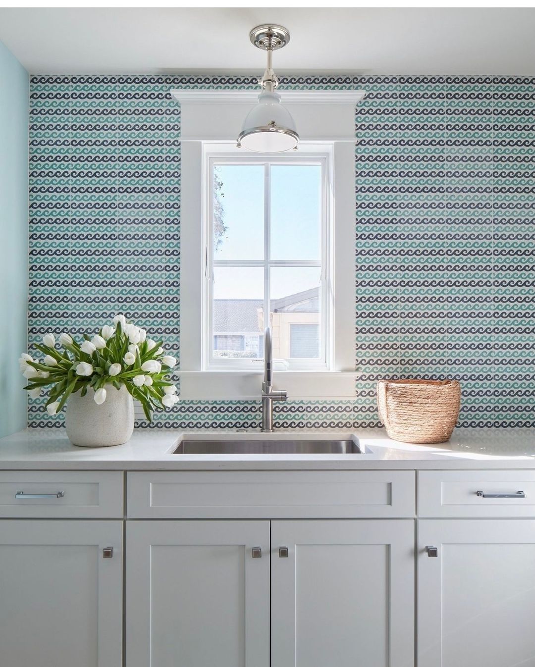 Bright and airy kitchen with a wave-patterned backsplash and fresh flowers on the countertop