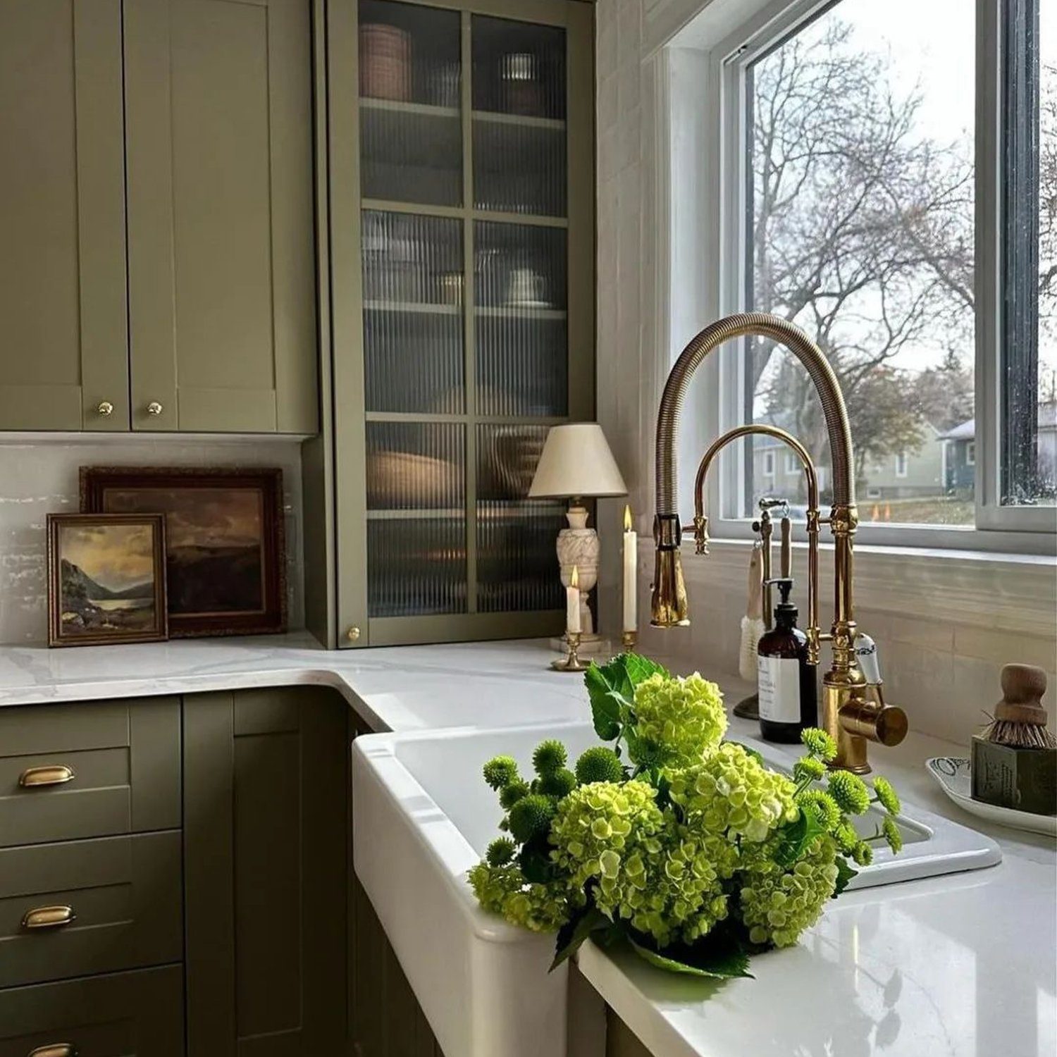 Elegant kitchen design featuring olive green cabinets, a farmhouse sink, and brass fixtures