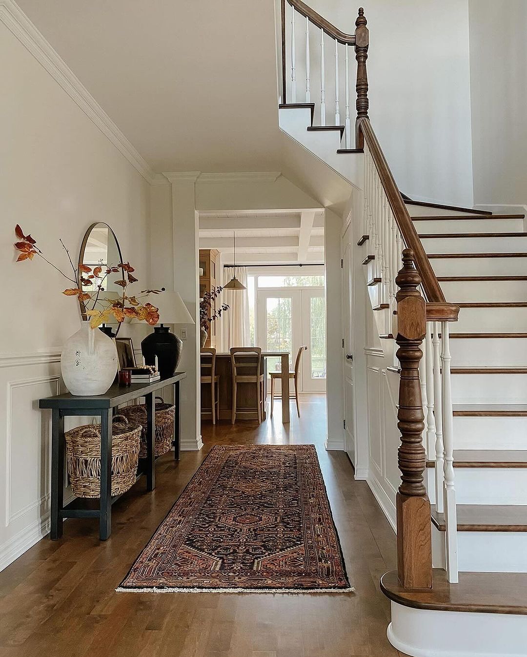 An inviting entryway featuring a warm-toned Persian rug and a classic wooden staircase