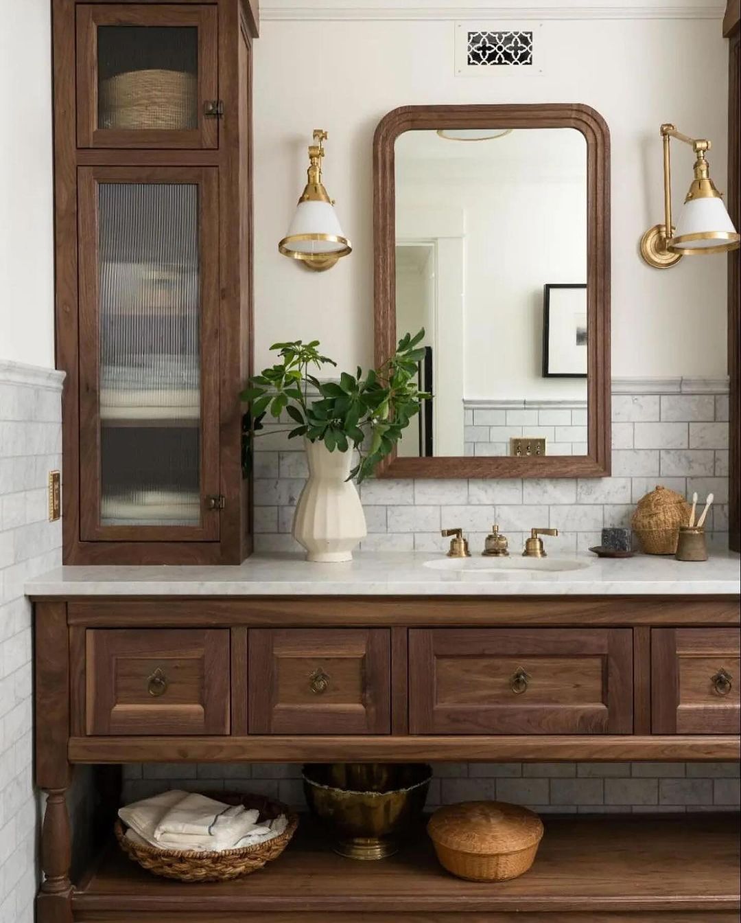 A classic bathroom setup featuring wood-toned cabinetry and brass fixtures