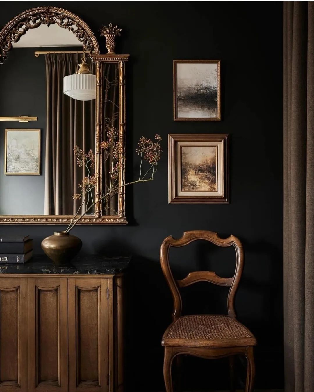 A tastefully decorated dark-themed room featuring classical artwork and furniture.