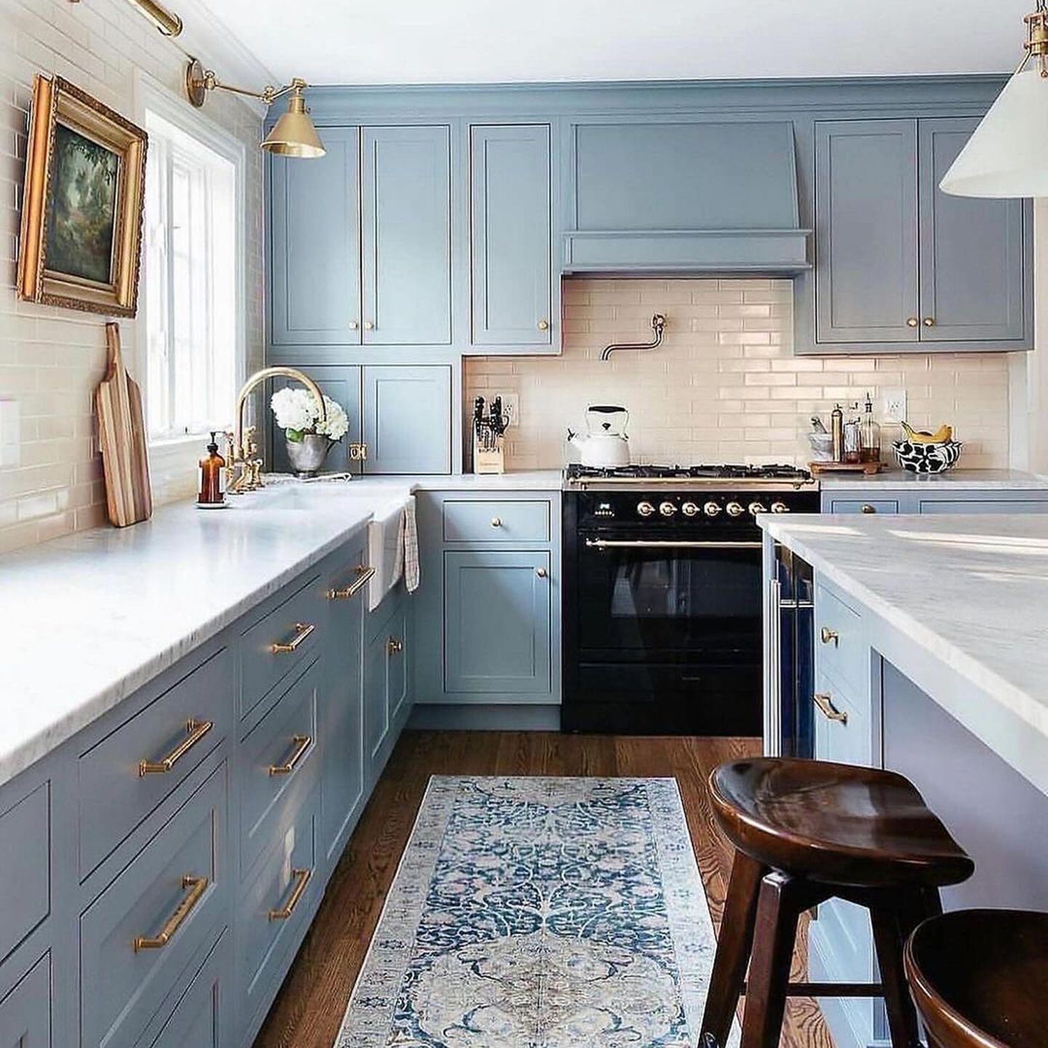 Elegant blue kitchen space featuring brass hardware and a classic subway tile backsplash