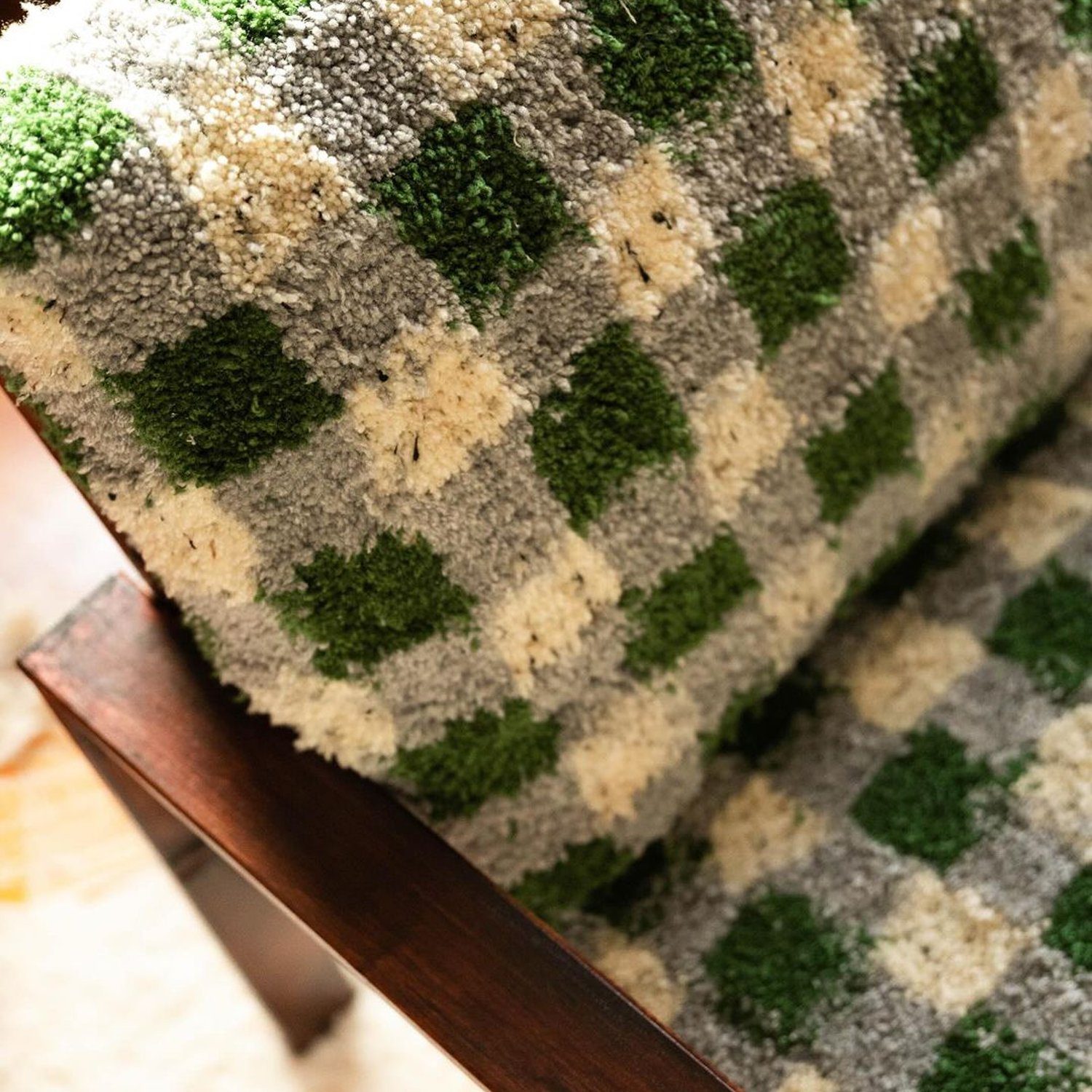 A close-up view of a textured armchair with a houndstooth pattern in shades of green and beige