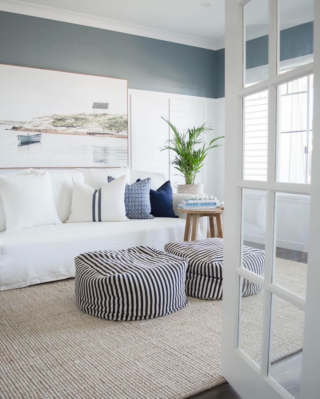 A chic coastal-inspired living room featuring striped poufs and nautical accents