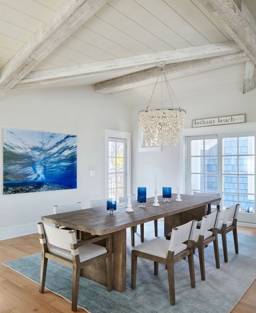 A chic coastal dining room with exposed beams and a seashell chandelier