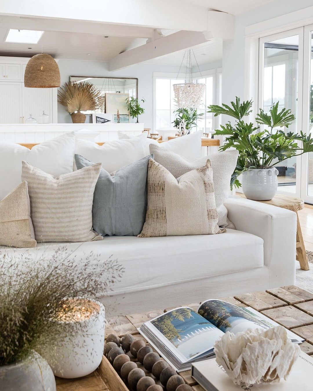 A modern beach-inspired living room with an array of plush cushions on a white sofa