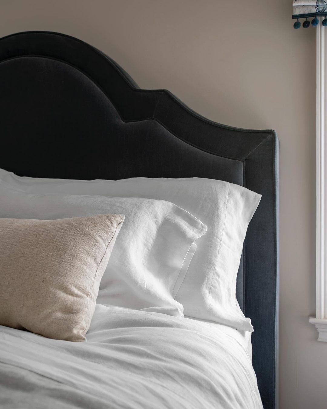 A neatly made bed with a dark upholstered headboard